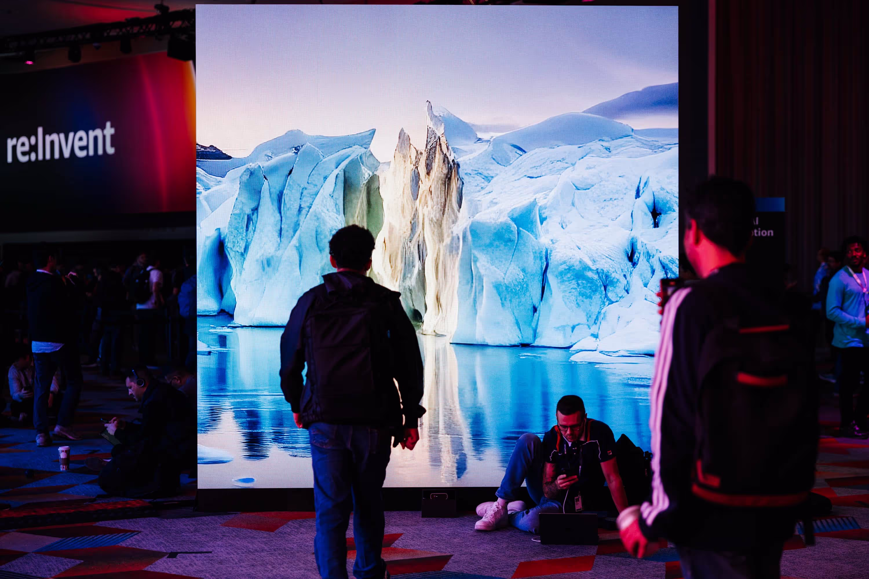 A man standing in front of a large screen with icebergs