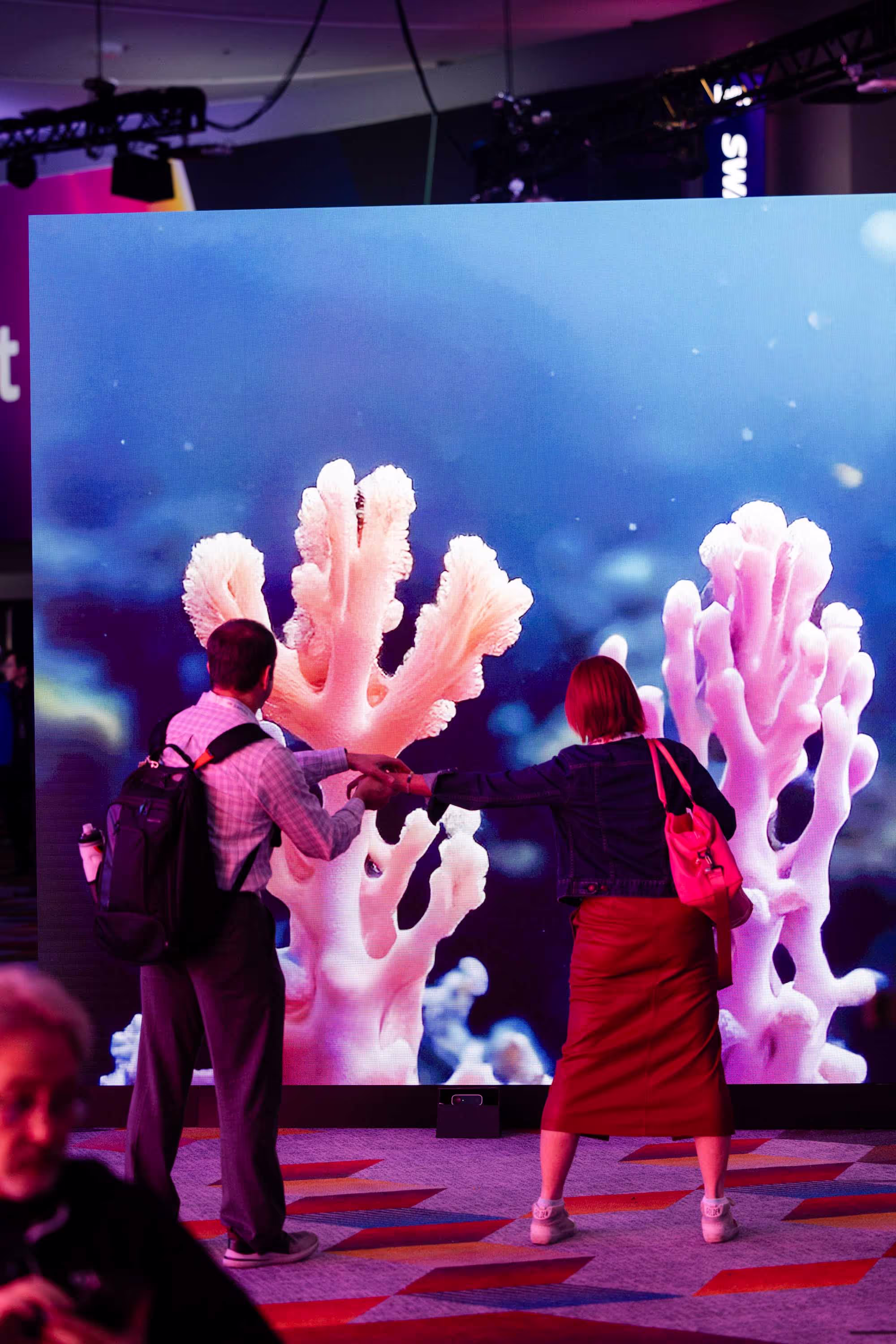 A group of people standing in front of a large screen