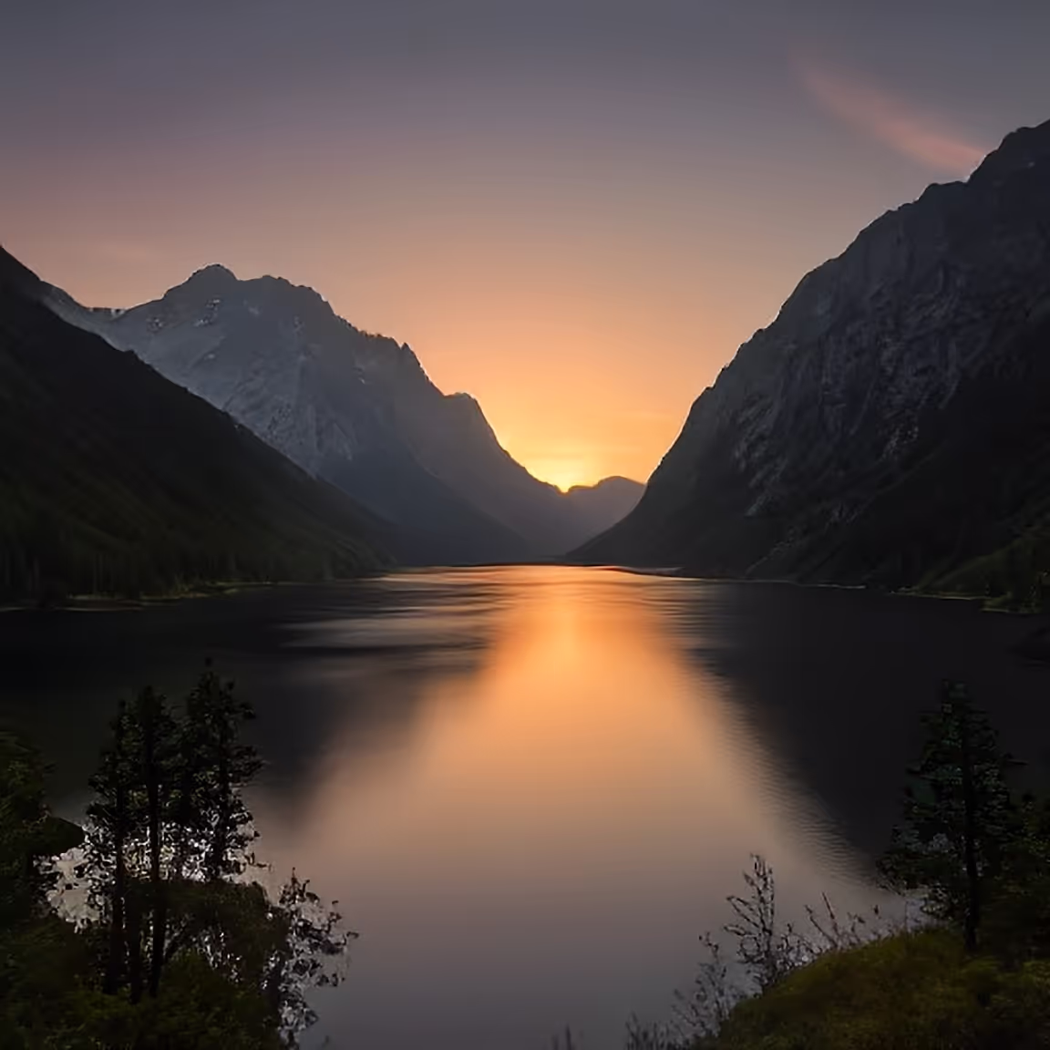 The sun is setting over a mountain lake
