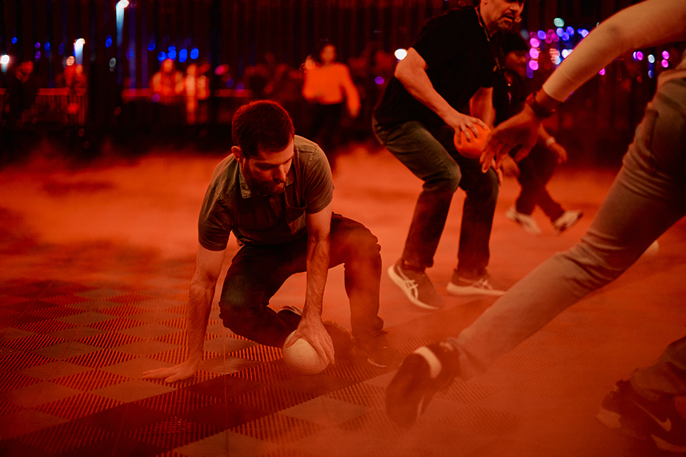 Players diving for the ball on the smoky Dodgeball court