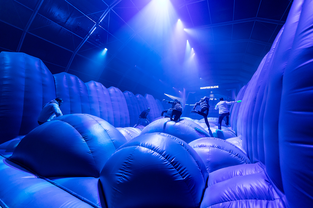 Guests climbing the blue-lit Gianter Slide inflatable