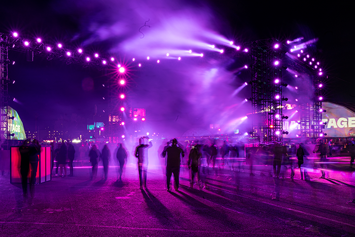 A group of people standing around a stage at night.