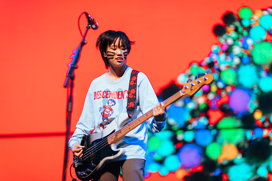A young man playing a bass guitar on stage.