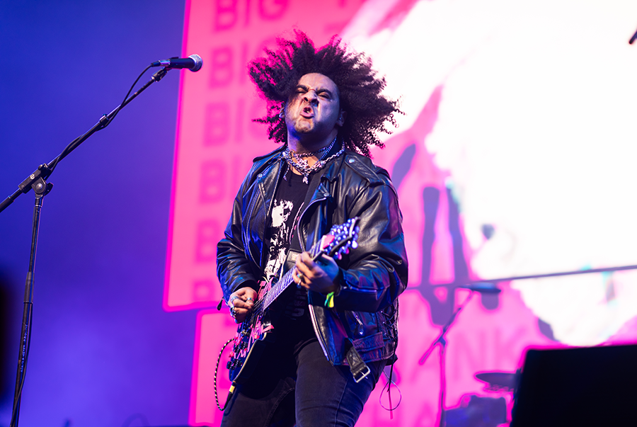 A man with dreadlocks standing in front of a microphone.