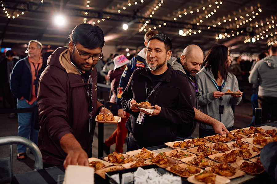 A group of people standing around a table filled with food.