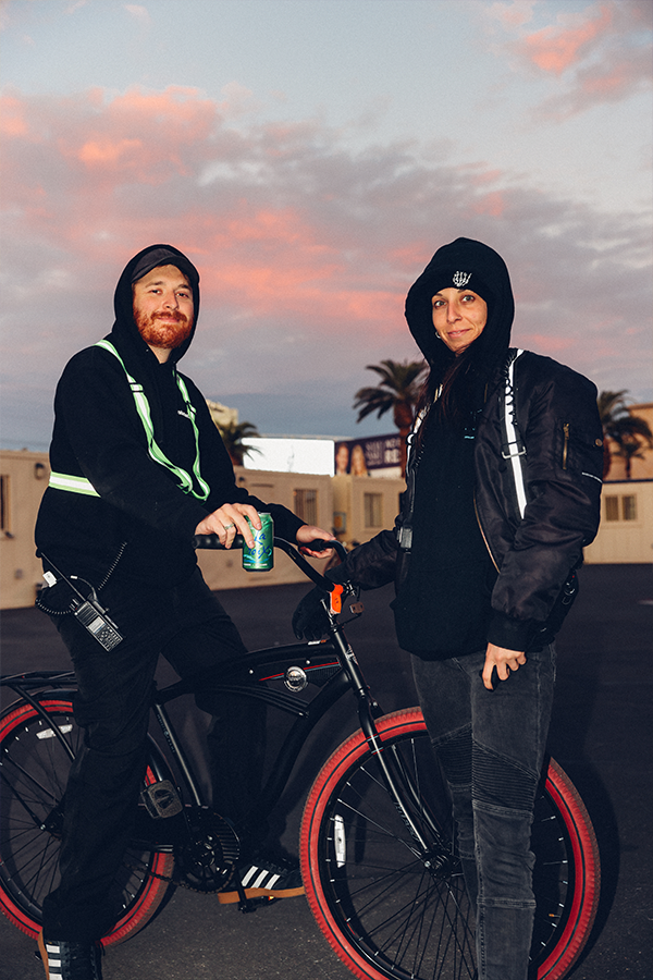 A man and a woman standing next to each other on a bike.