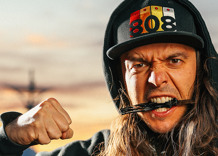 A man with long hair wearing a hat and pulling on a string.