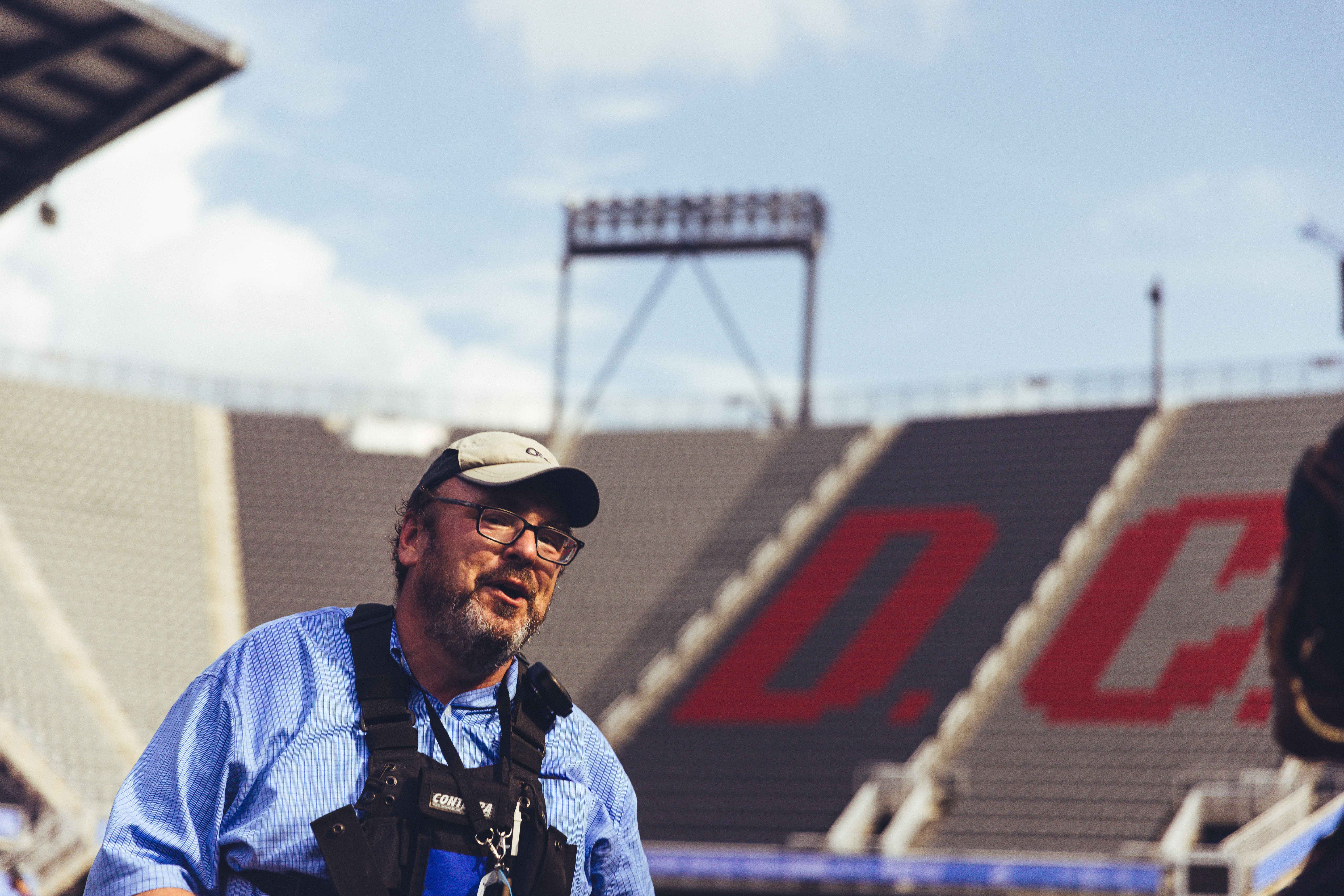 man in hat and blue shirt and standing in the middle of a stadium