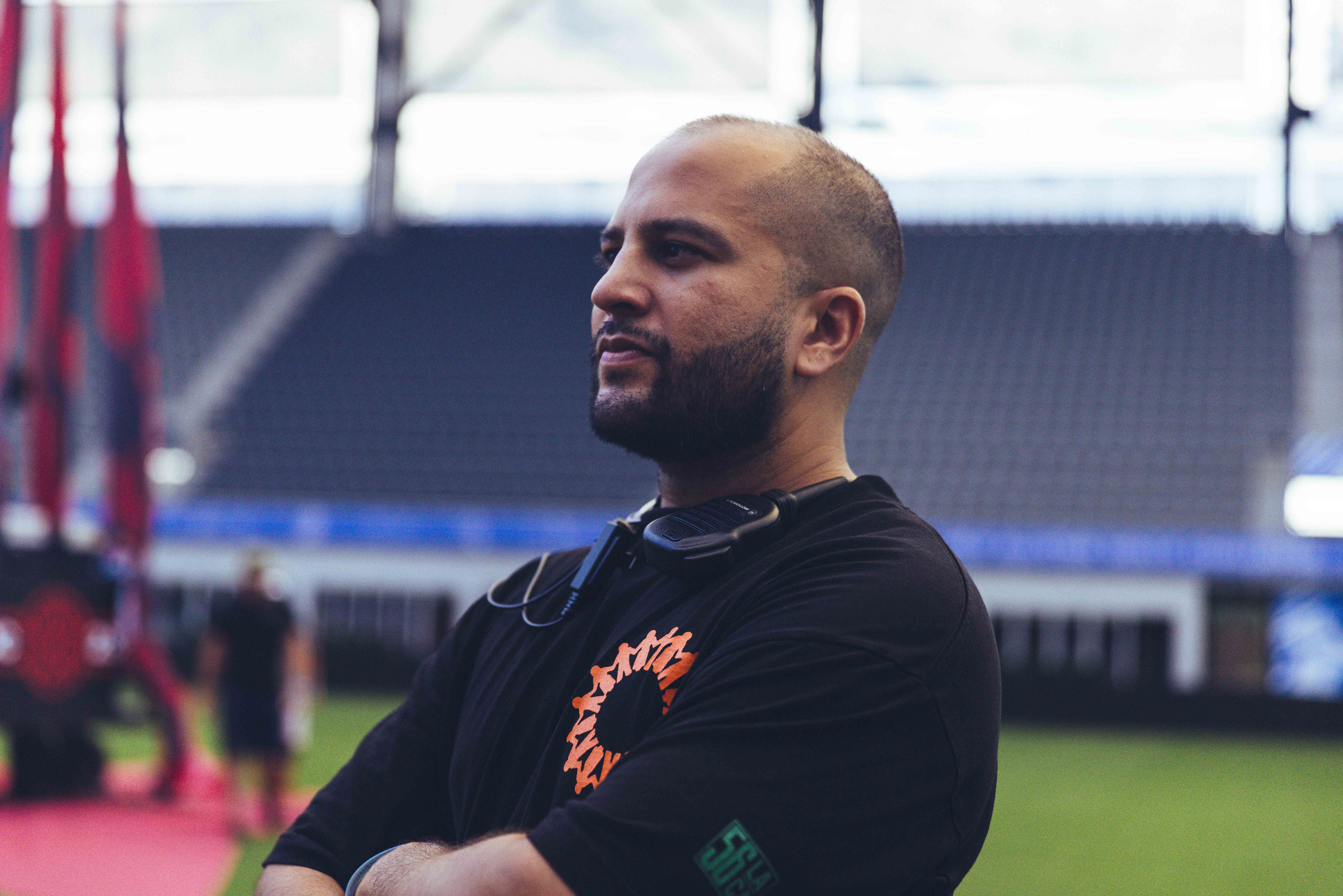 a man dressed in black crossing his arms in the middle of a soccer field