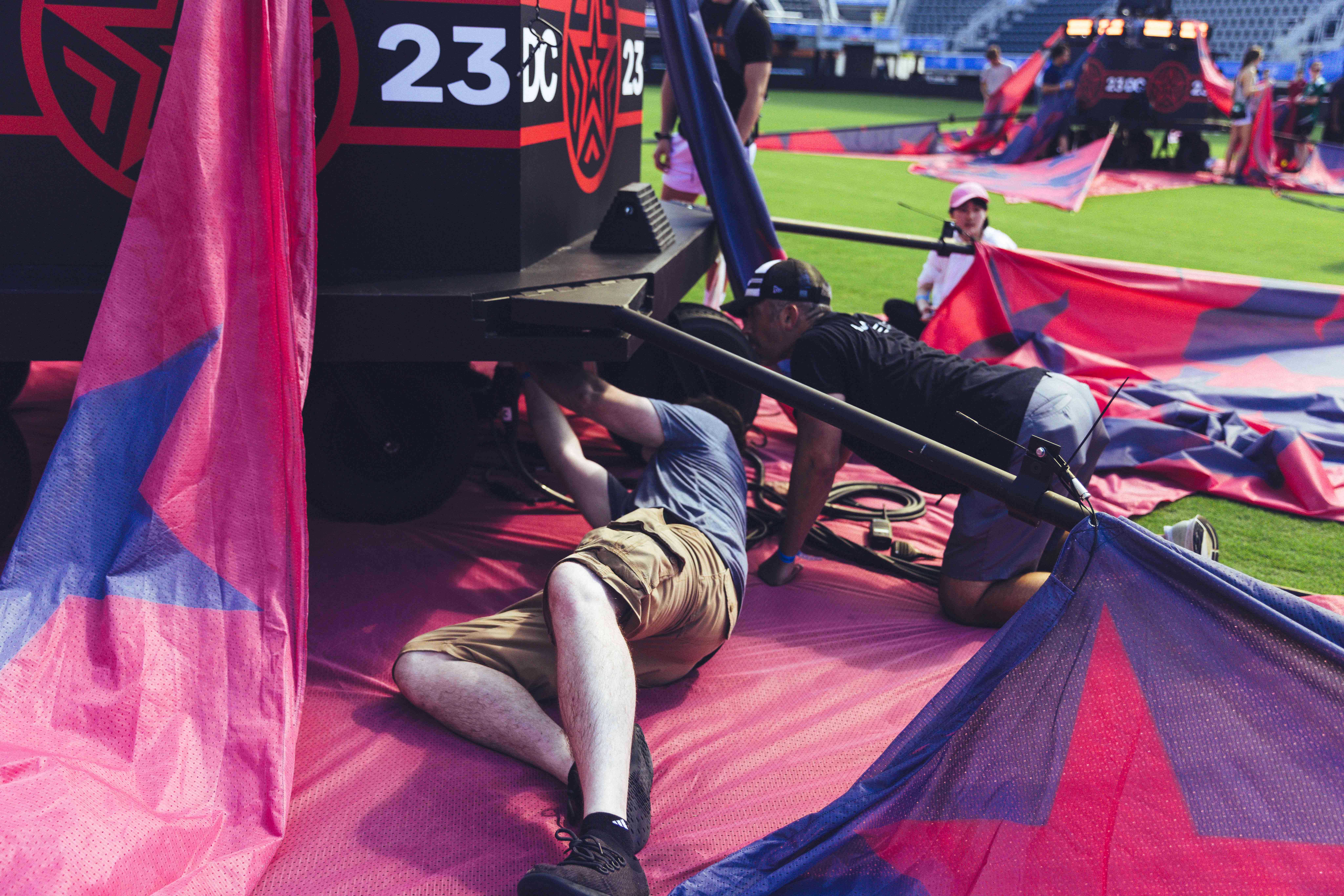 person laying down on a soccer field with red and black in the background
