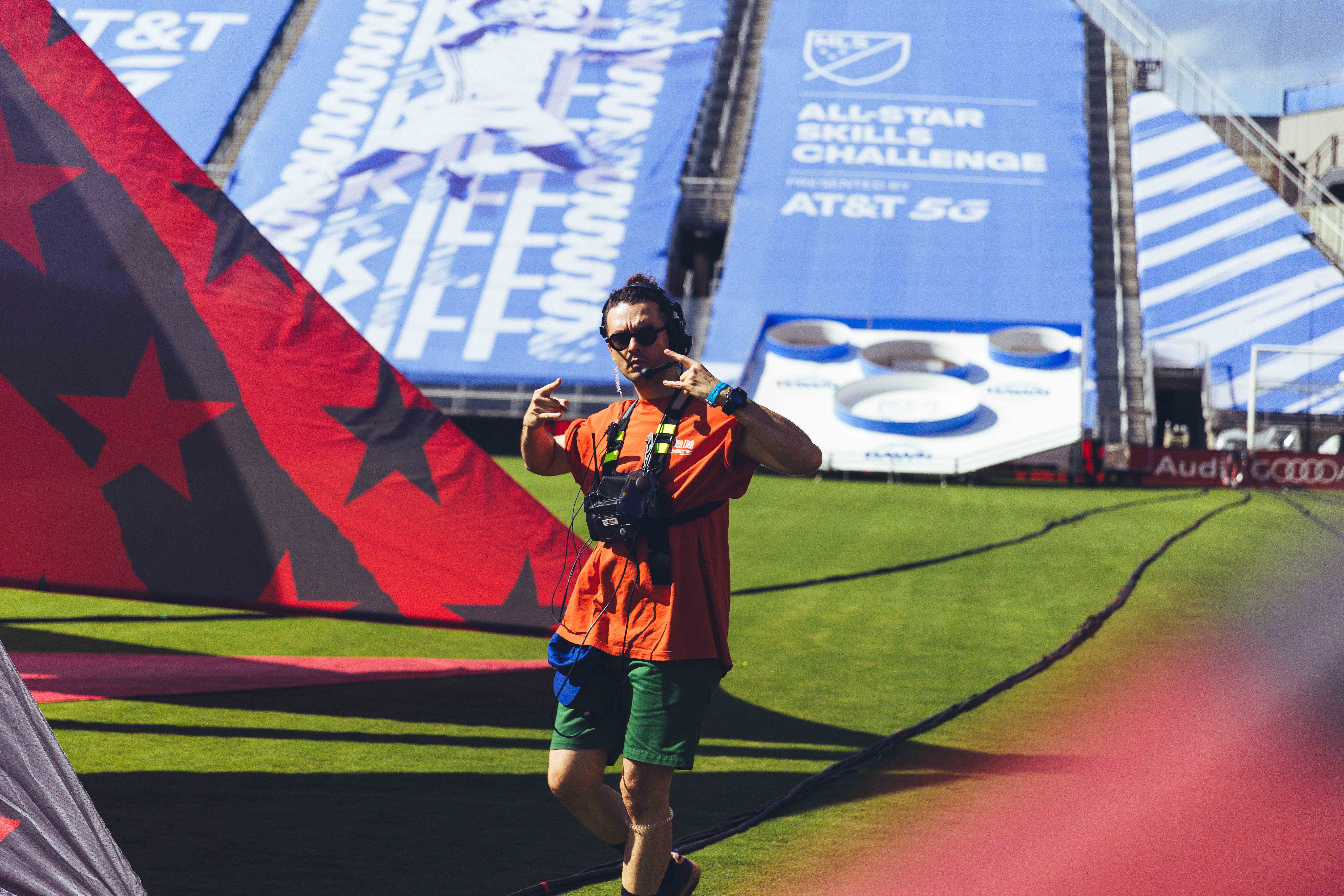 person standing on a soccer field with black and red flag in the background