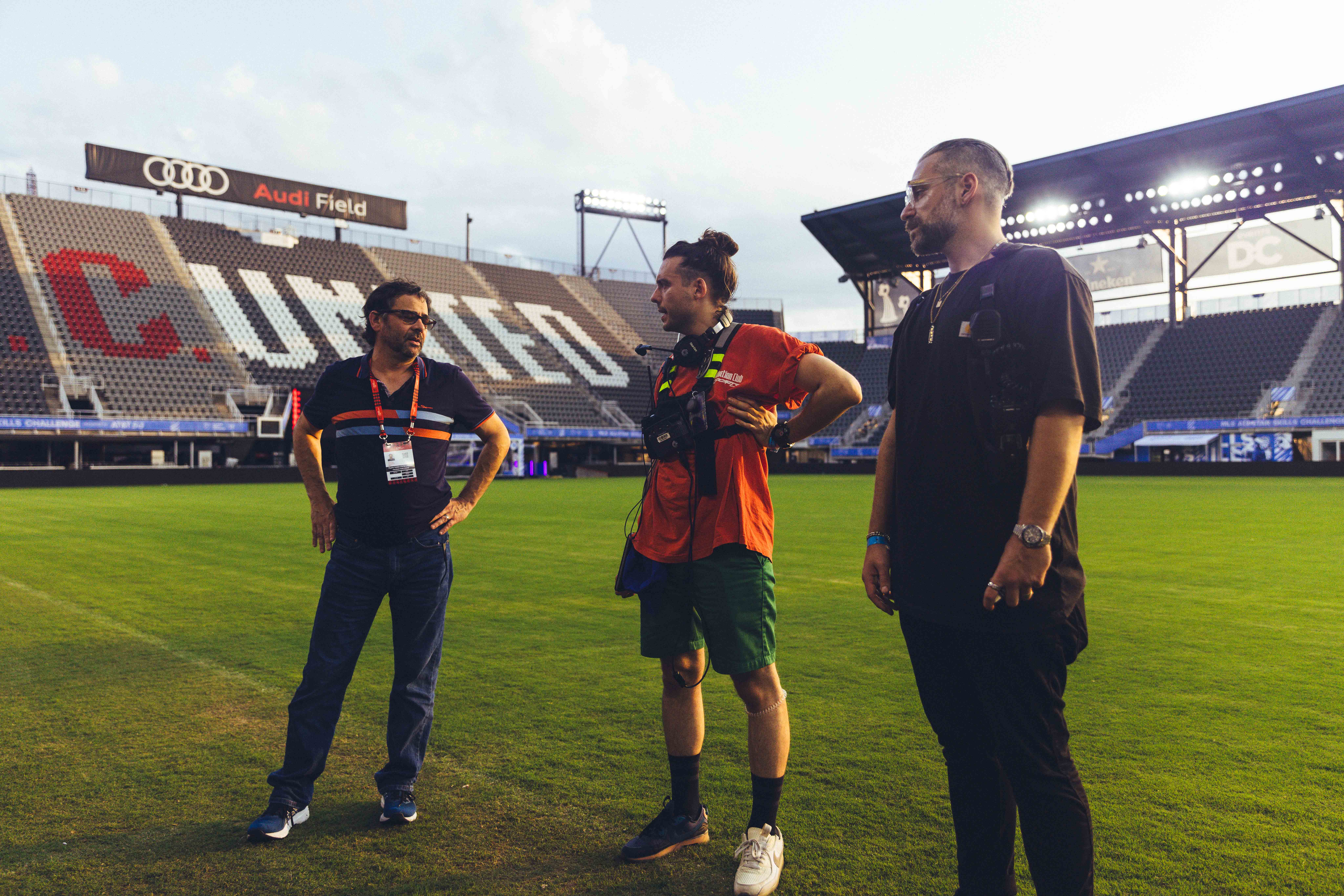 three people standing together and talking on a soccer field