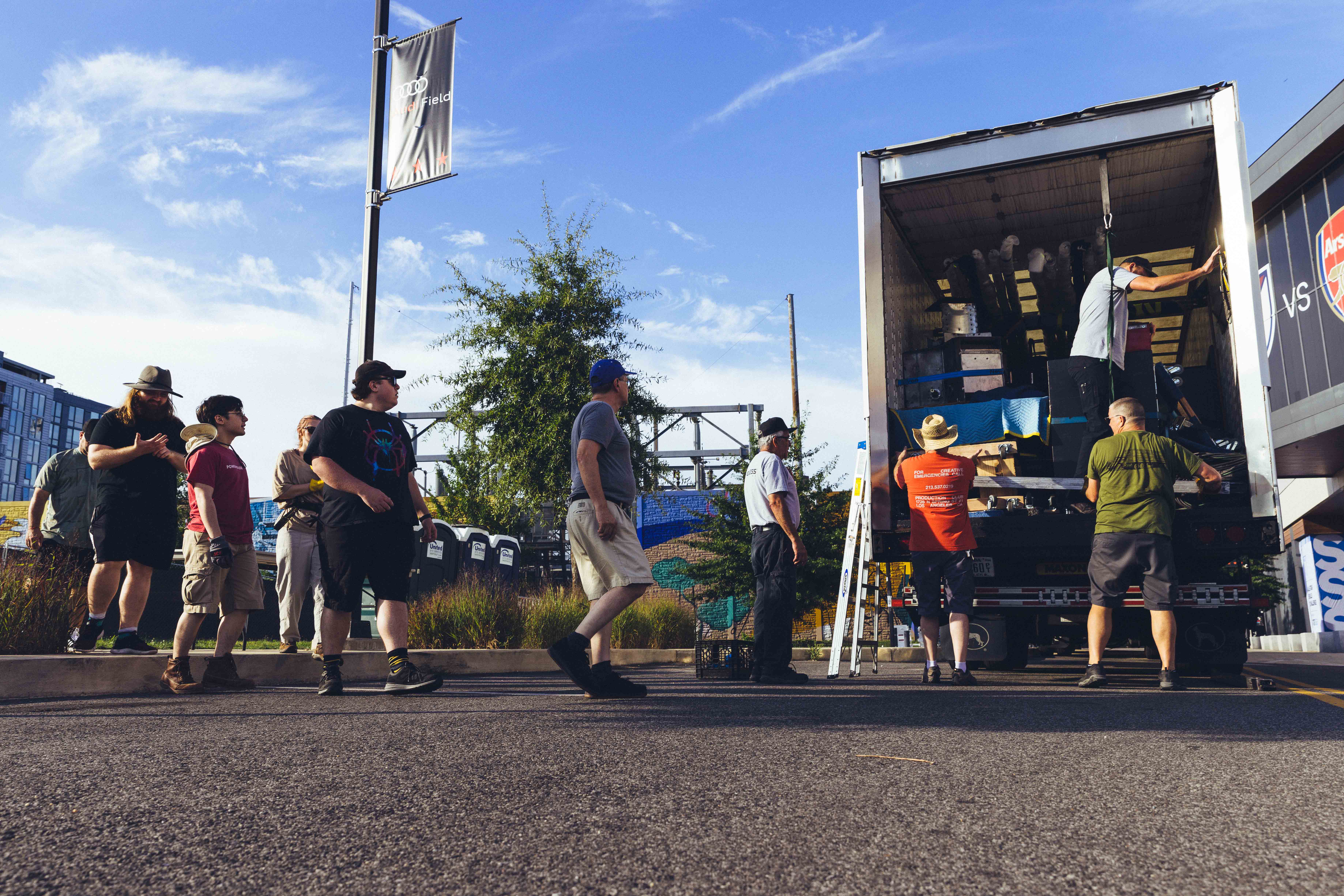 people standing around an open truck with a blue sky in the background