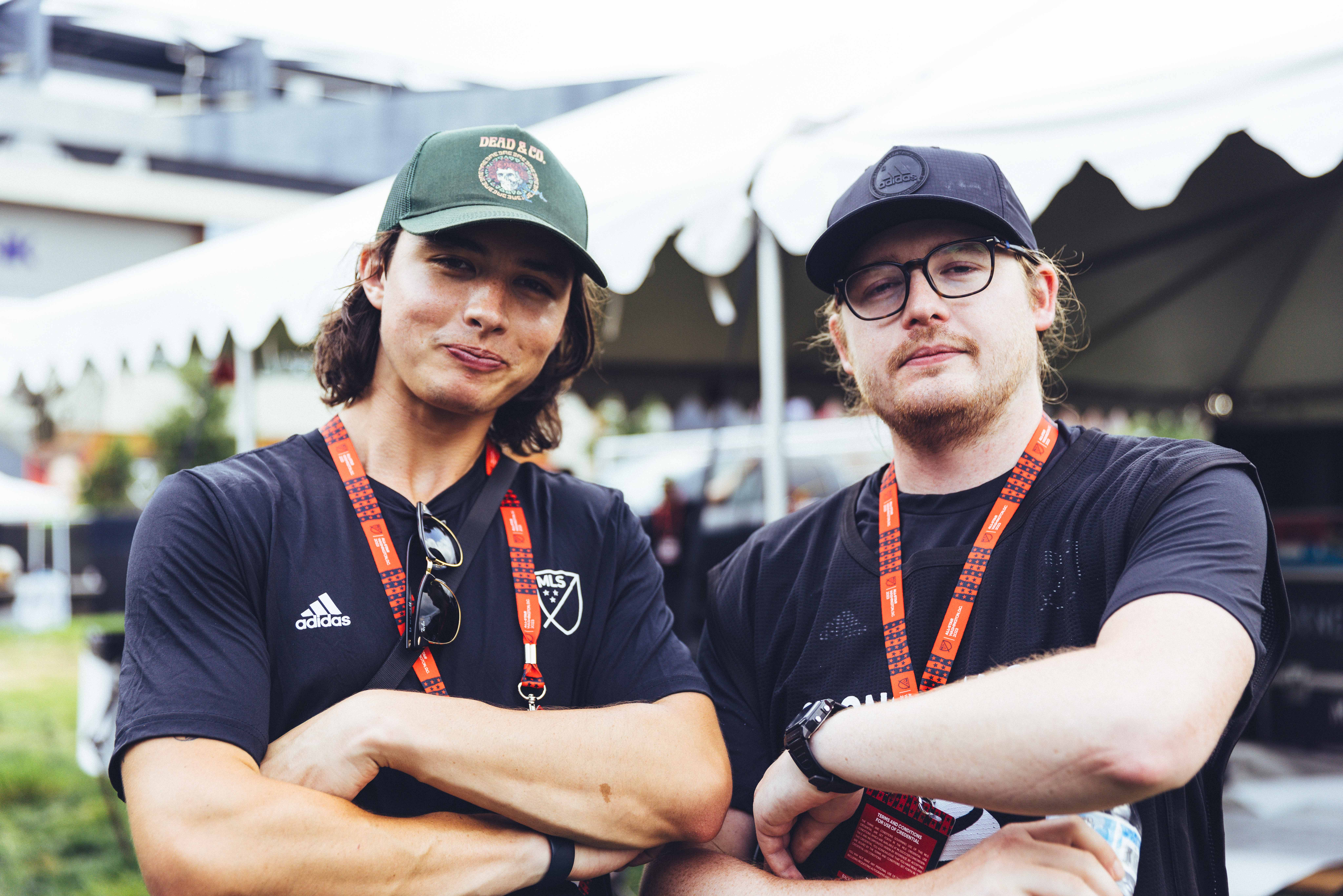 two people in black shirts pose with their arms crossed