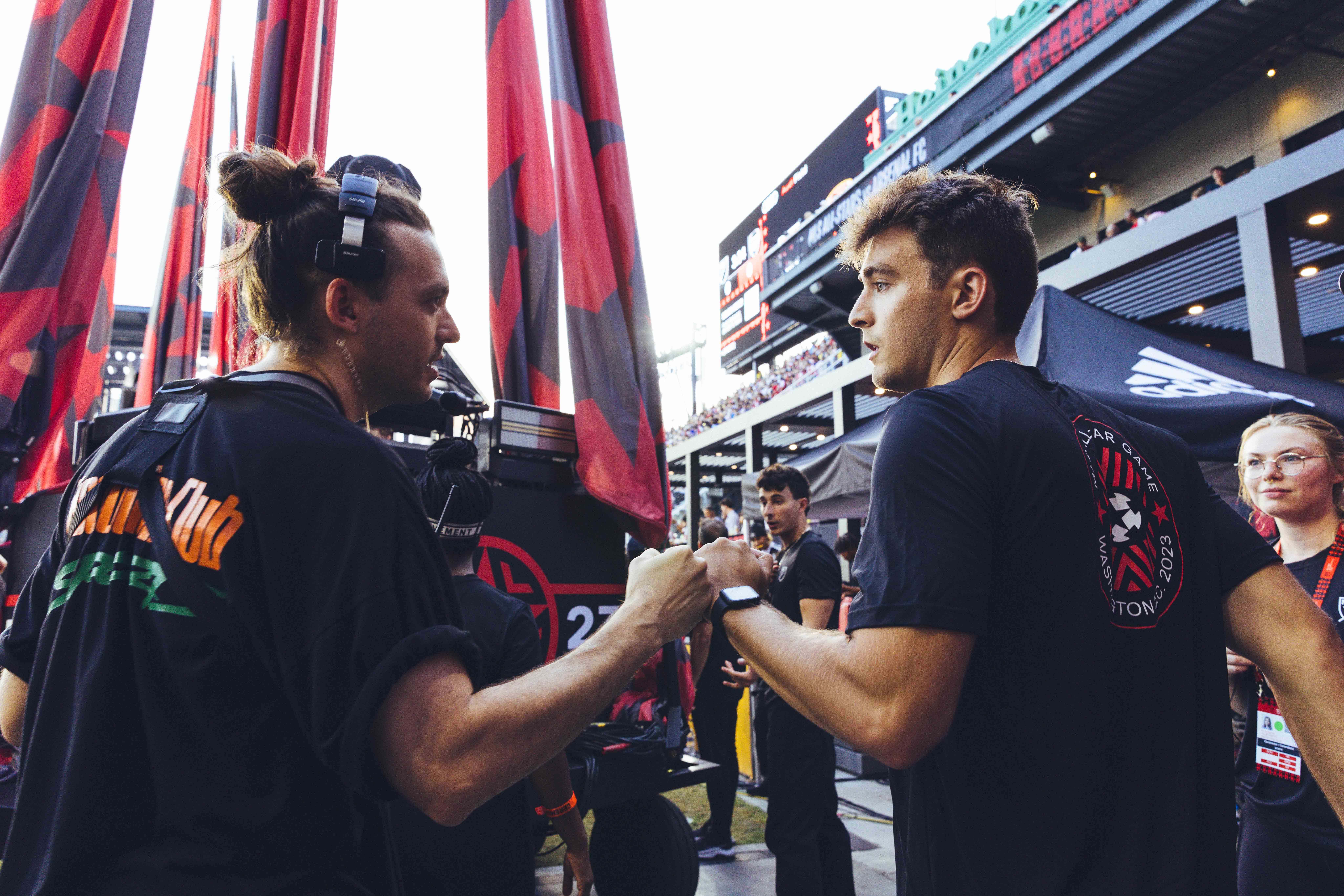 two people dressed in black shake hands with red and black flags in the background