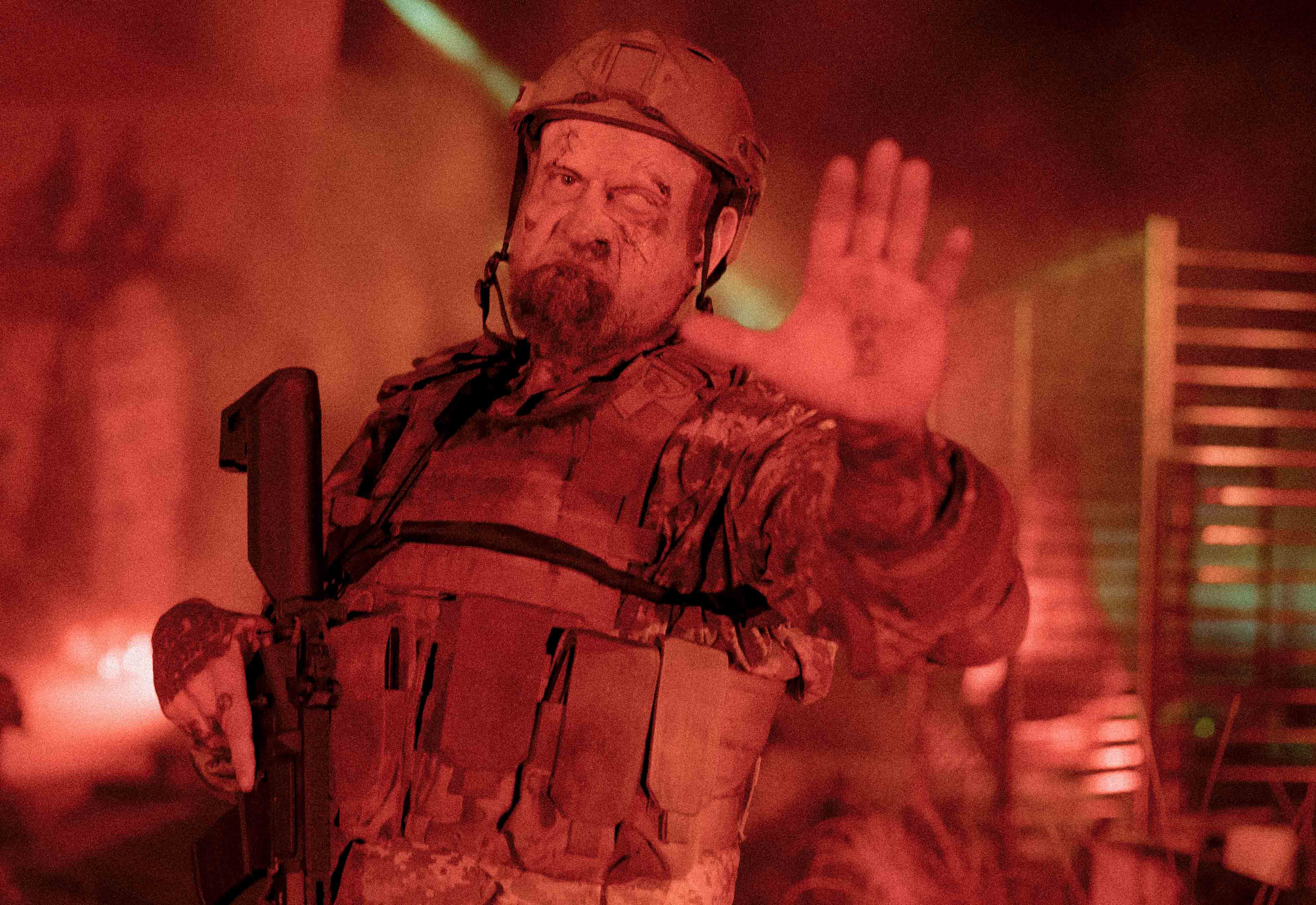 man dressed as military personnel holding his hand up with red lighting