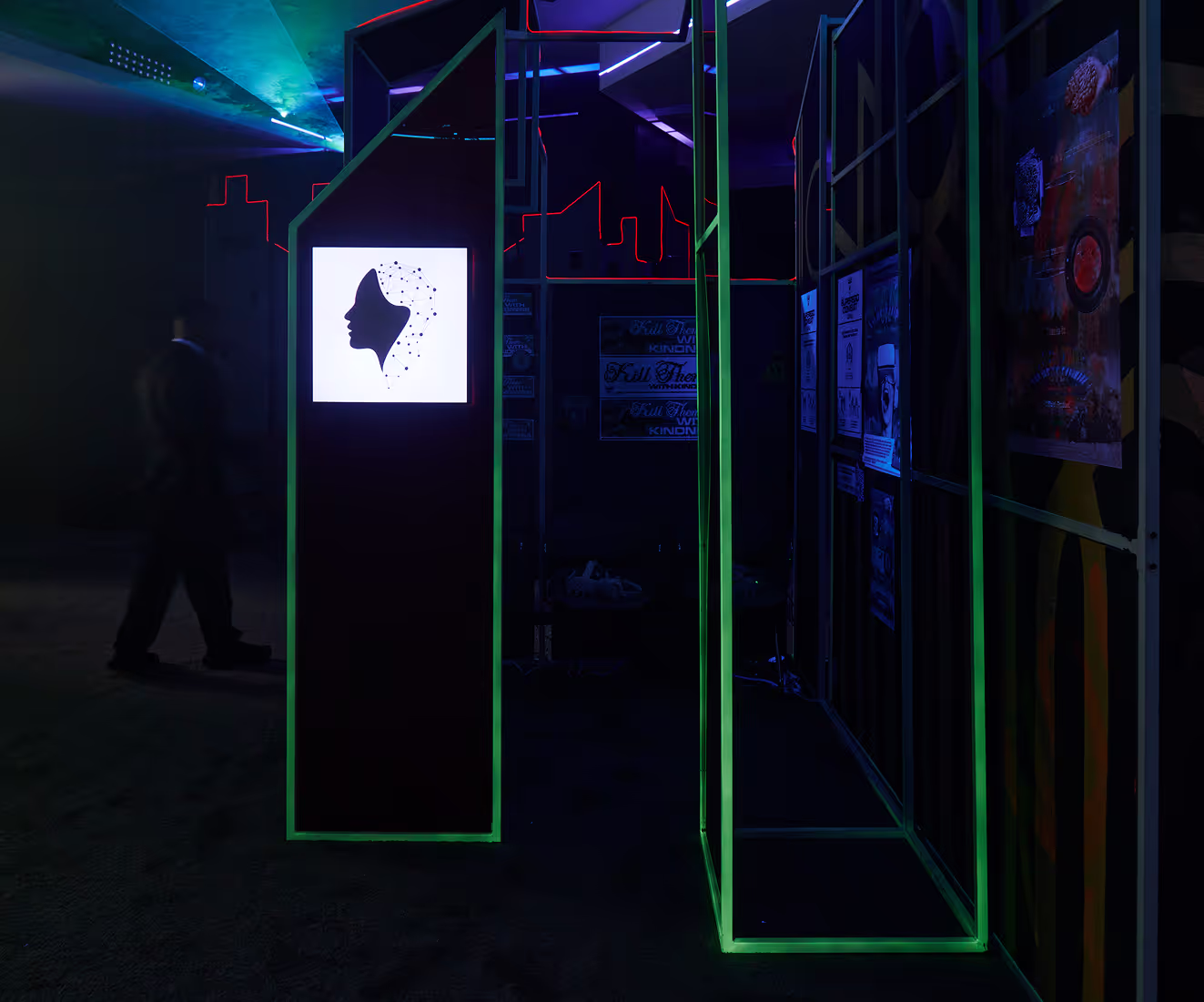 A man walking through a dark room with neon lights.