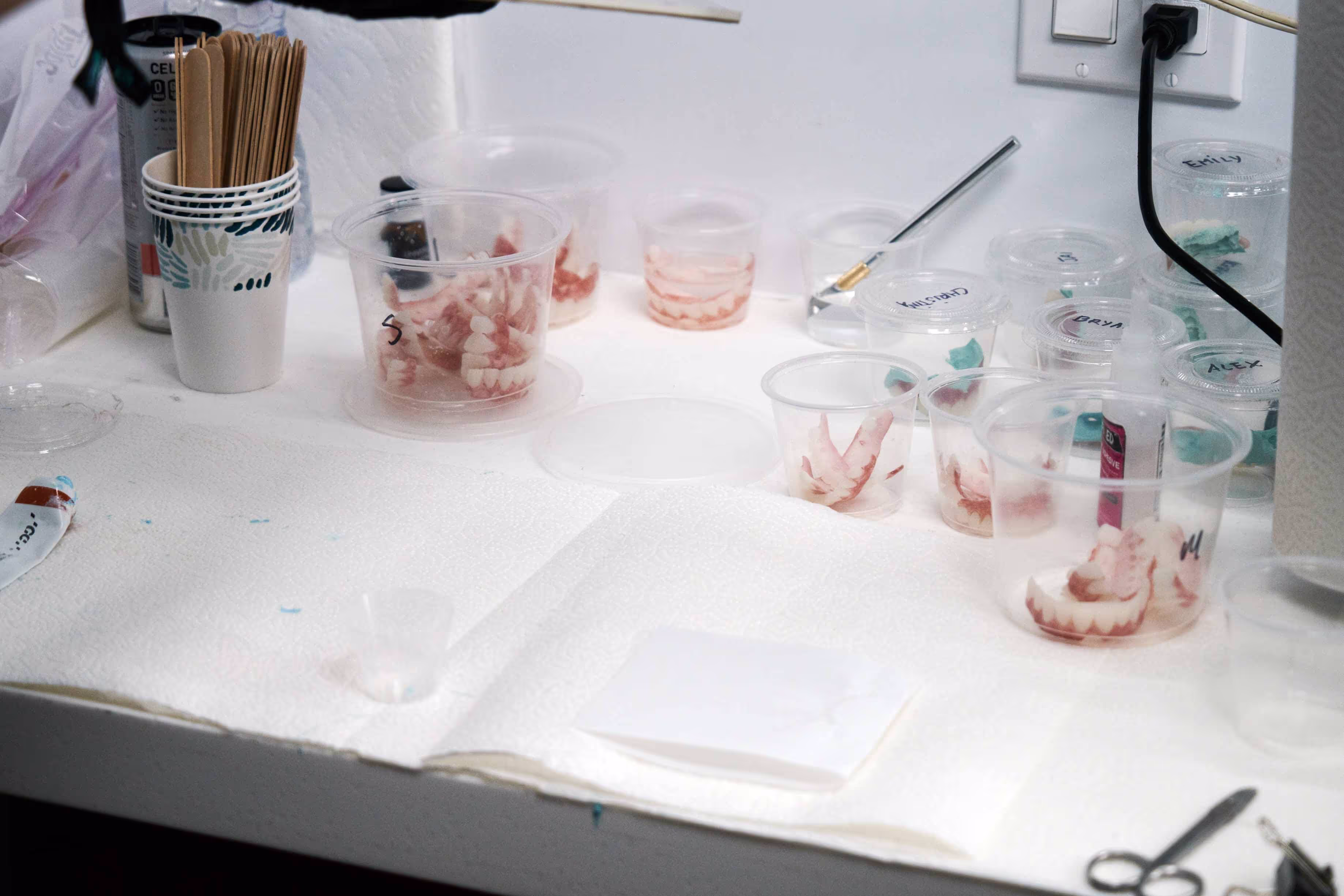 a counter with cups of dentures on them