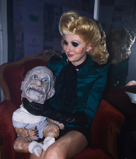 A woman sitting on a red chair holding a doll.