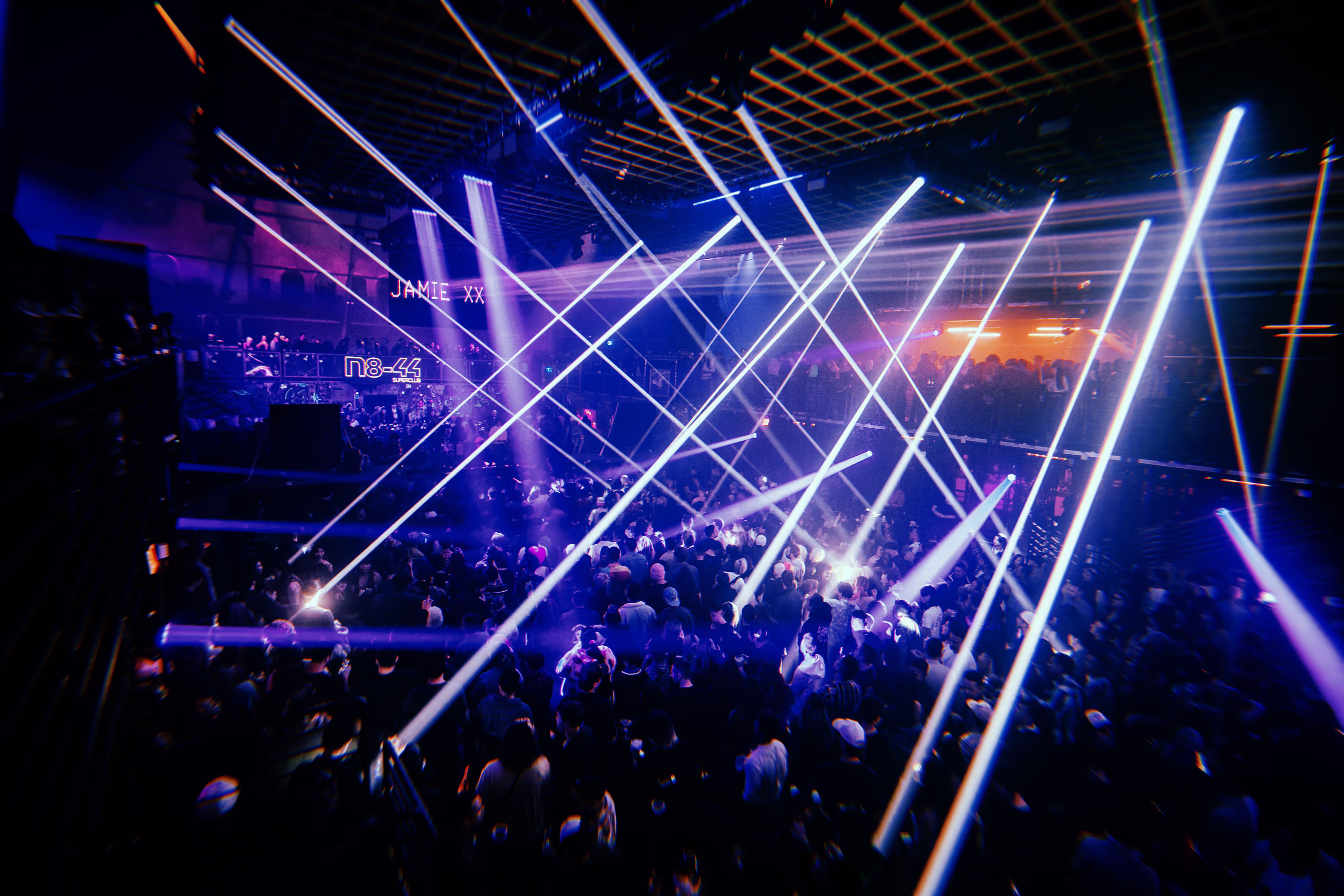 lasers in a warehouse rave with a crowd of people