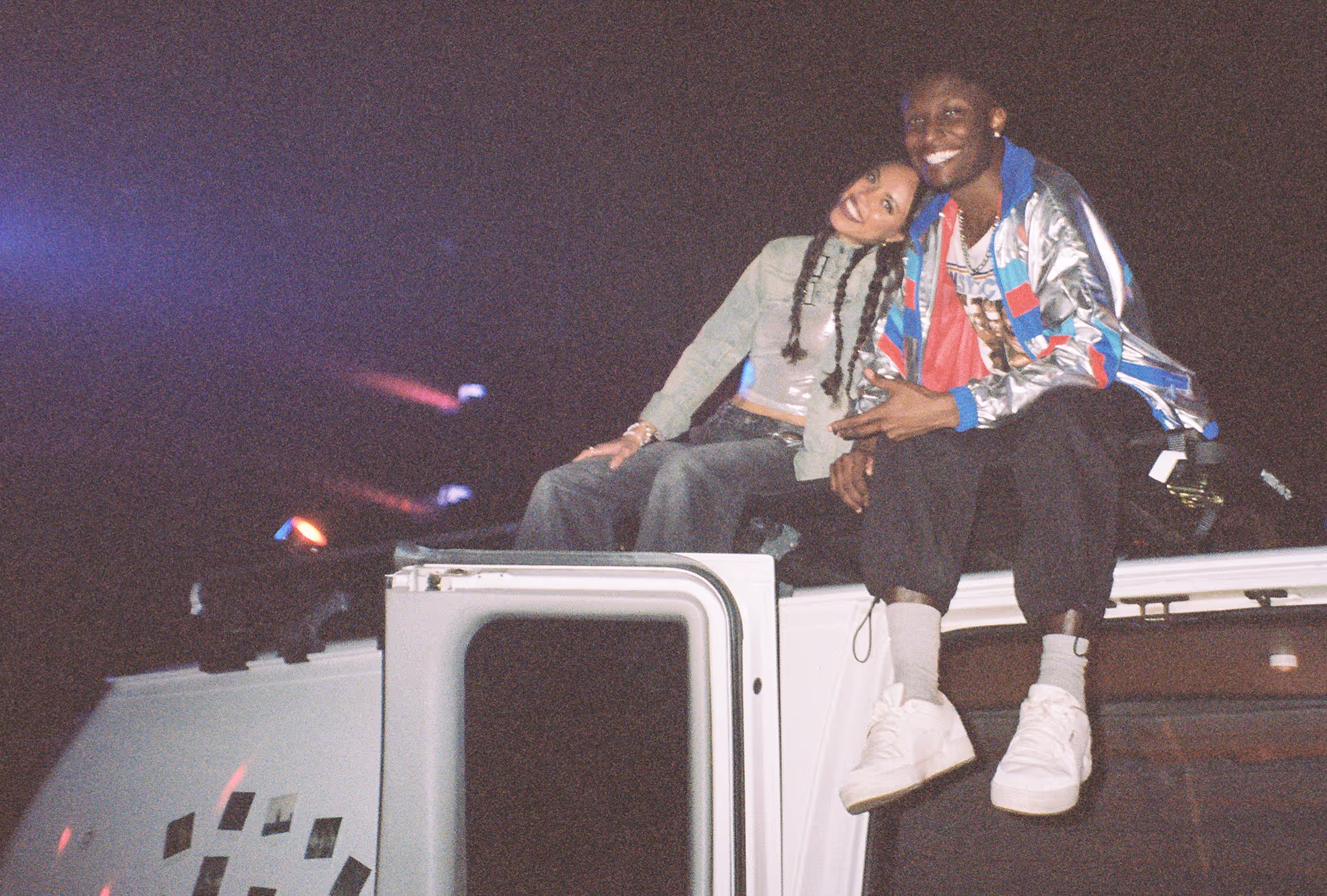 two people sitting on top of a van at a rave