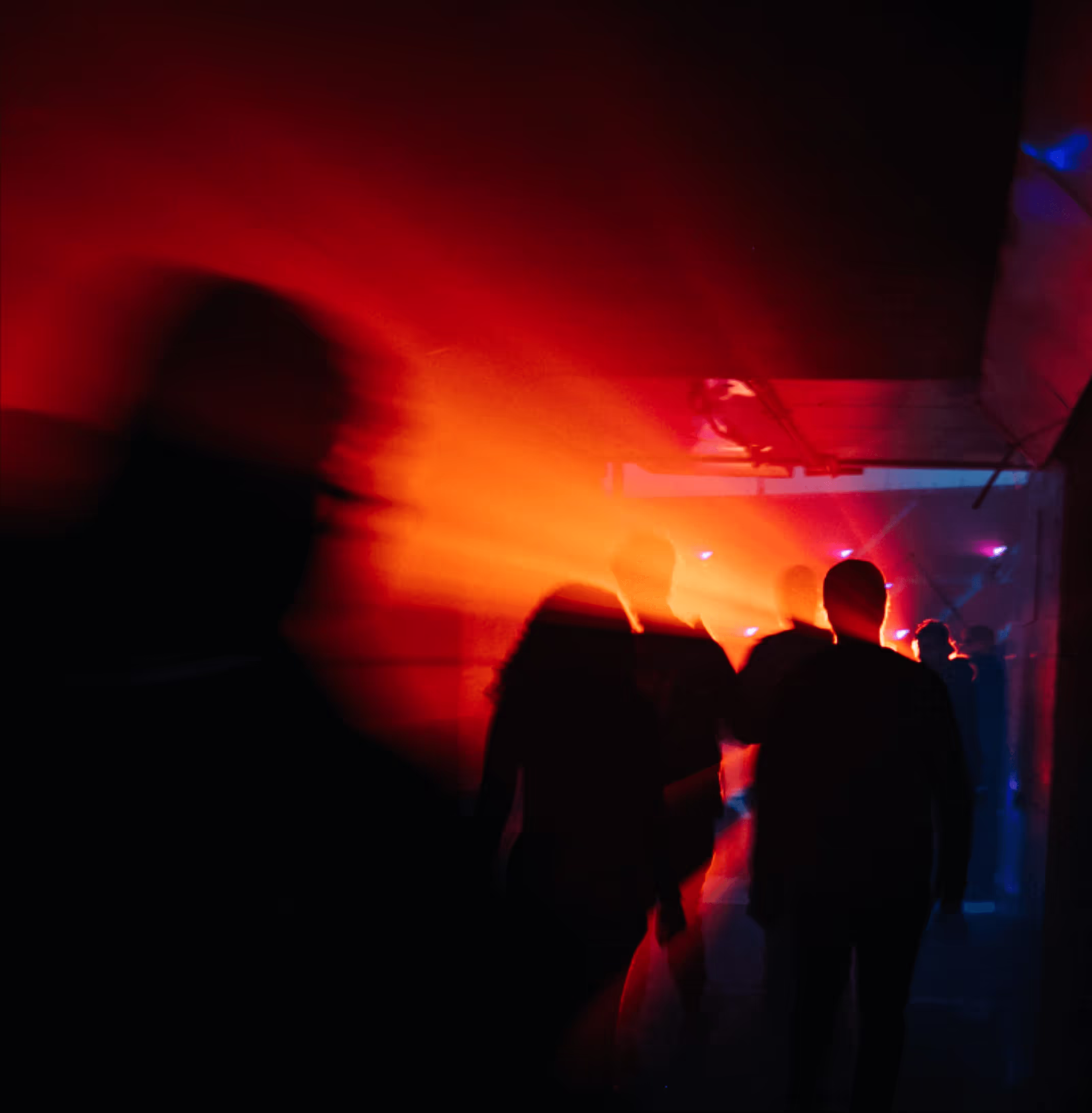 red backlit people walking through a tunnel