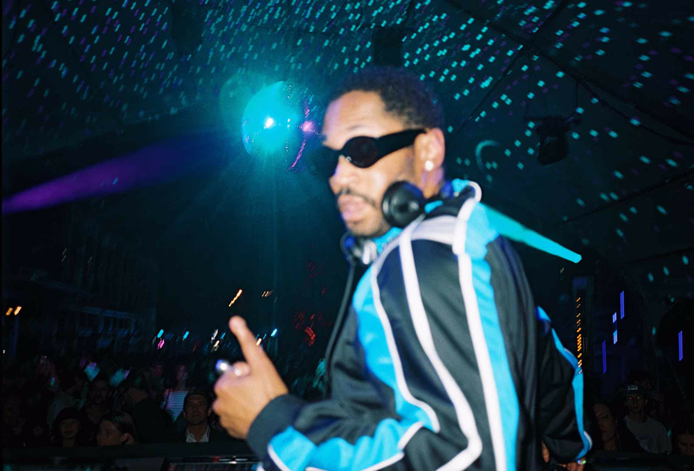 A man with headphones on standing in front of a crowd.