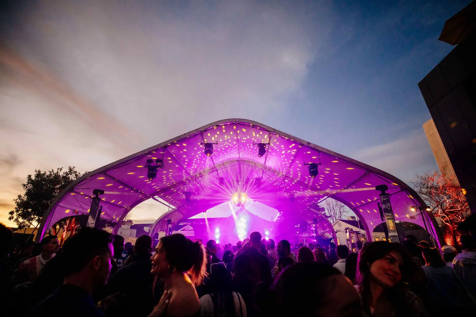 A group of people standing under a purple tent.