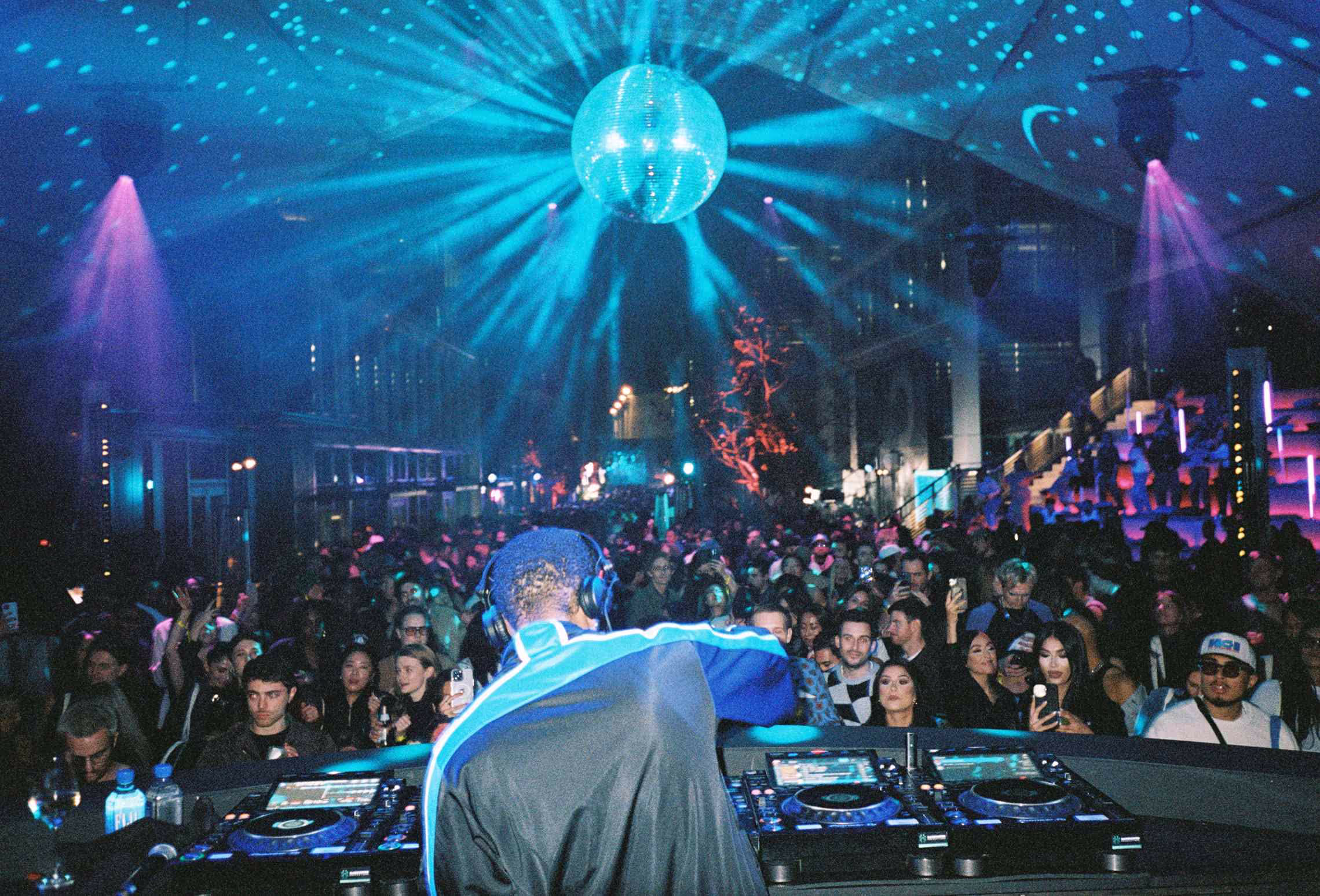 A dj in front of a large crowd of people.