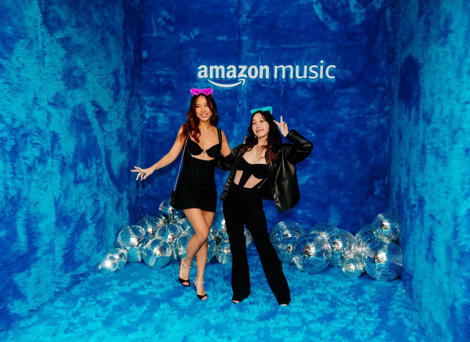 Two women posing for a picture in front of a blue backdrop.