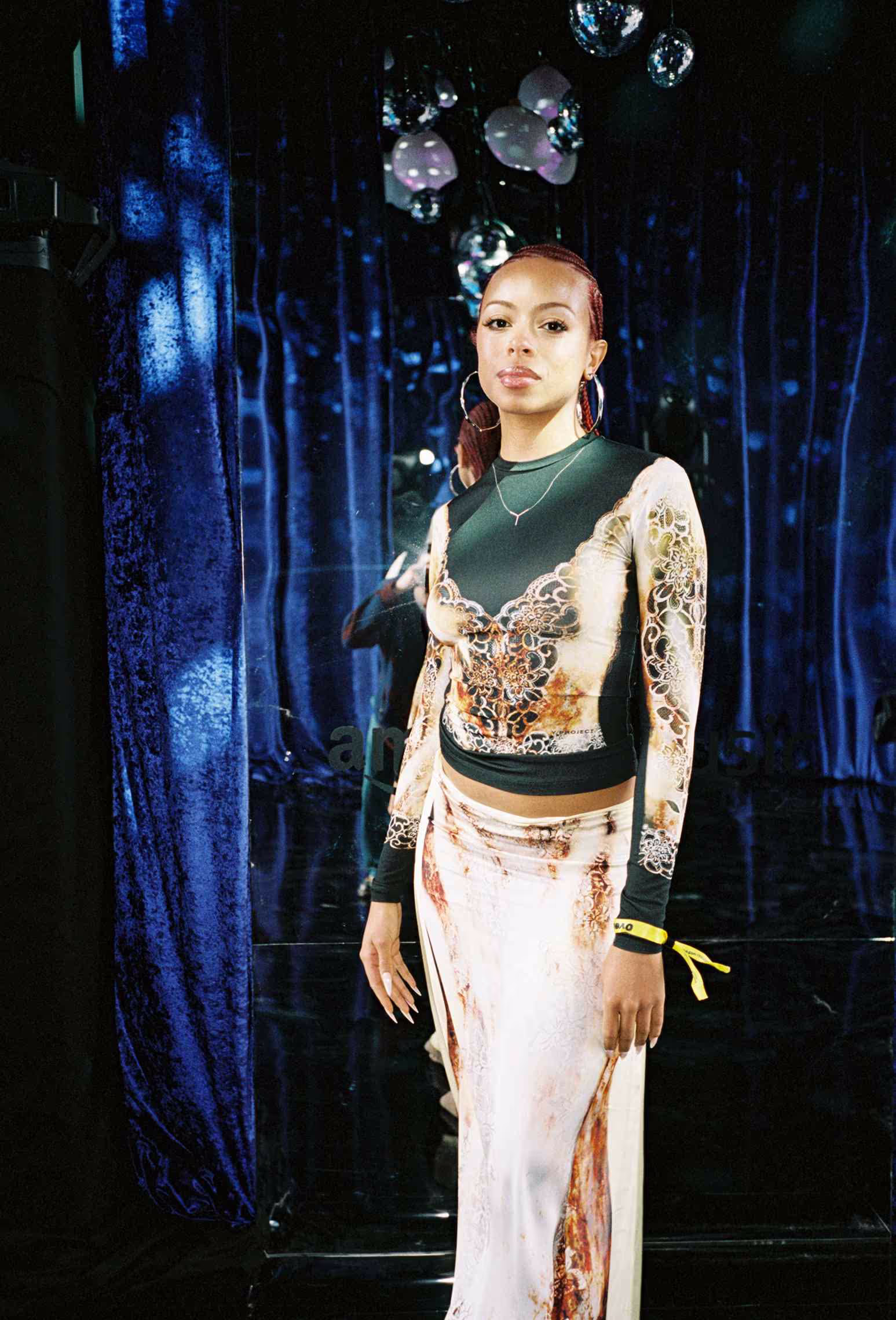 A woman standing in front of a blue curtain.
