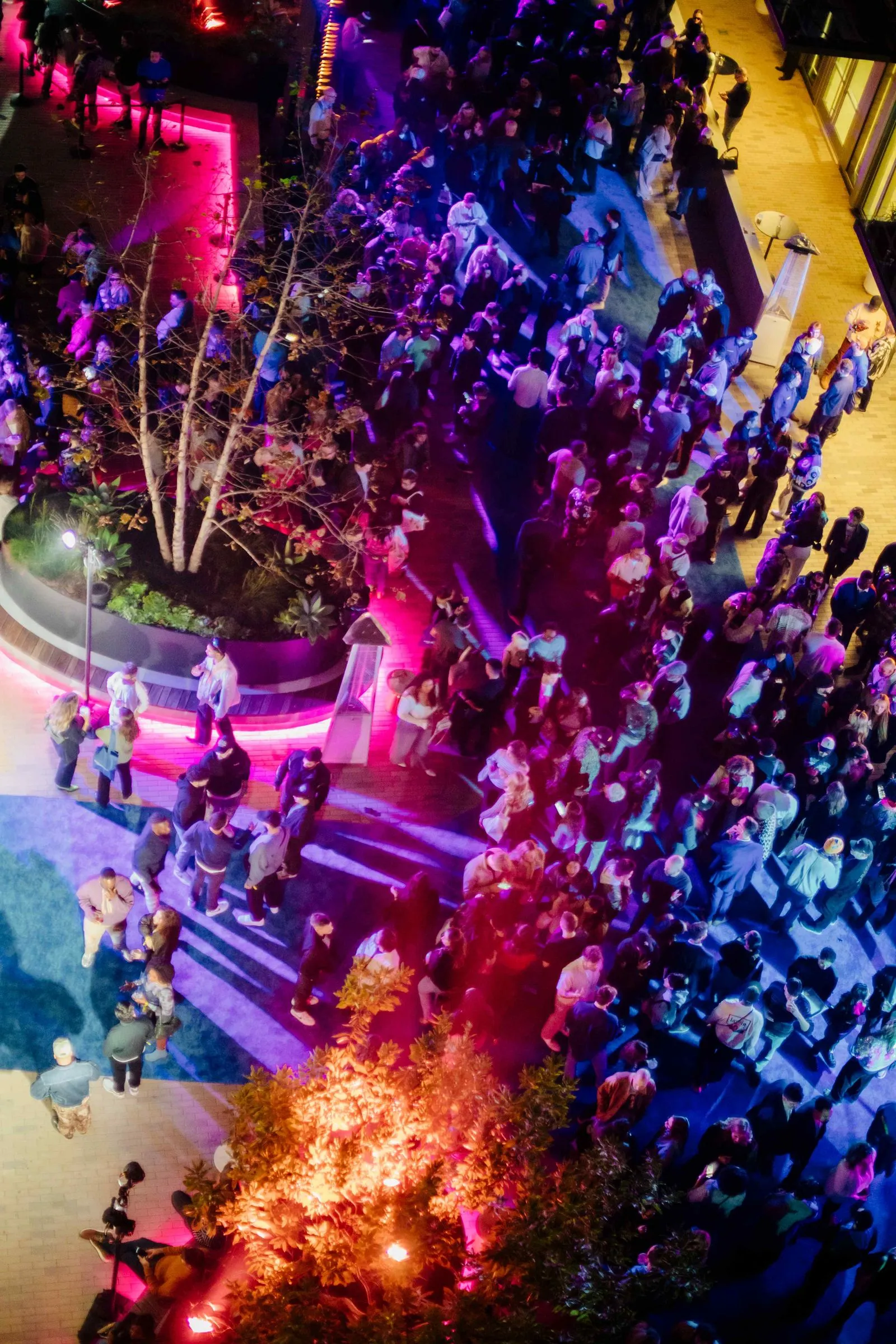 A crowd of people standing around a pool at night.