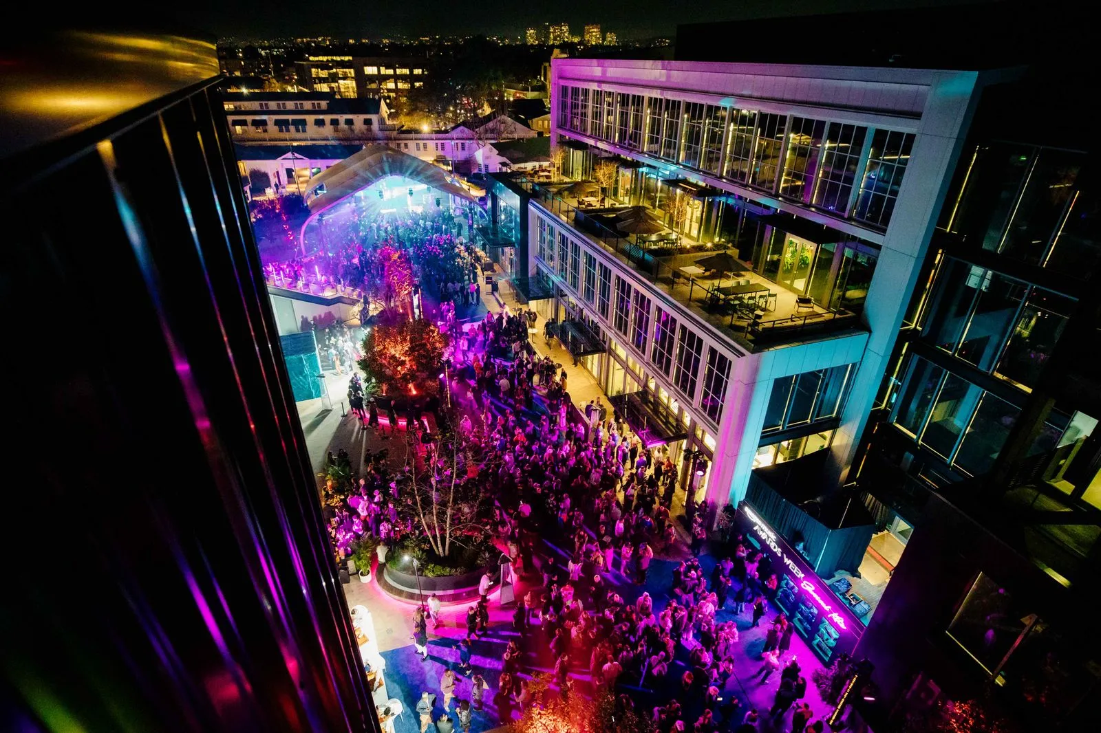 A crowd of people standing around a building at night.