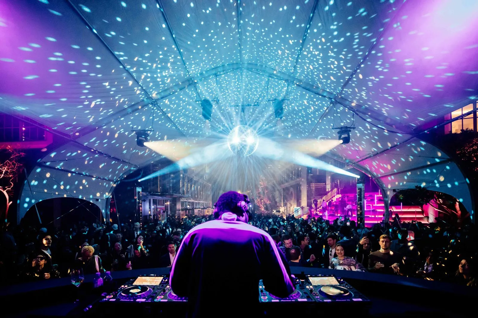 A dj in front of a large crowd at a concert.