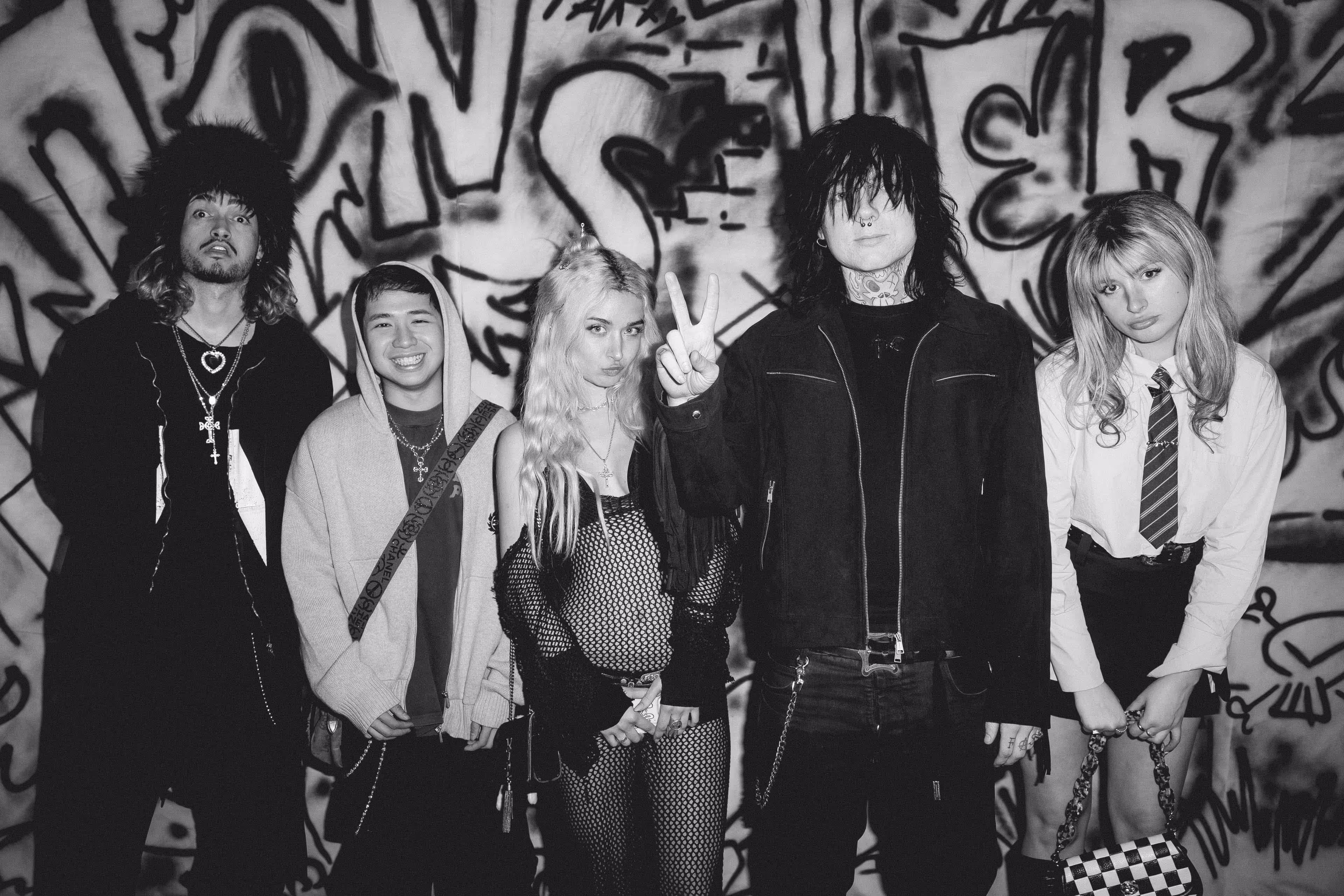 A group of people standing in front of a wall covered in graffiti.