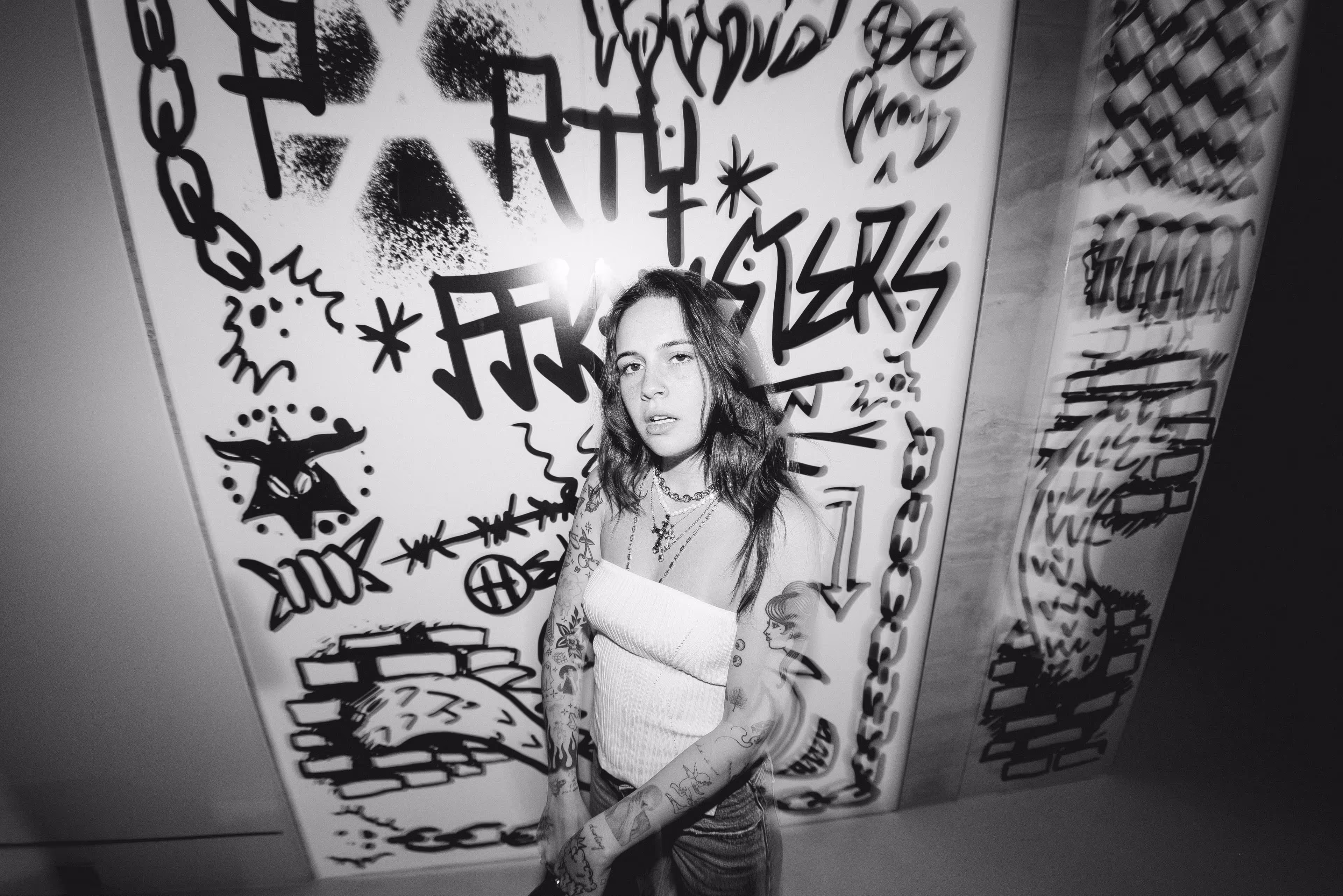 A woman standing in front of a wall covered in graffiti.