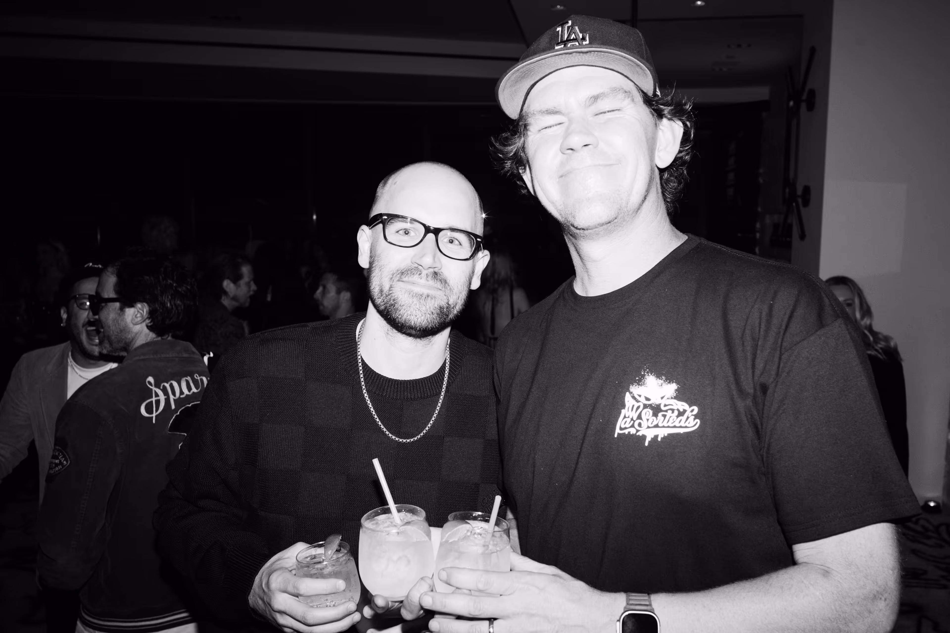 A couple of men standing next to each other holding drinks.