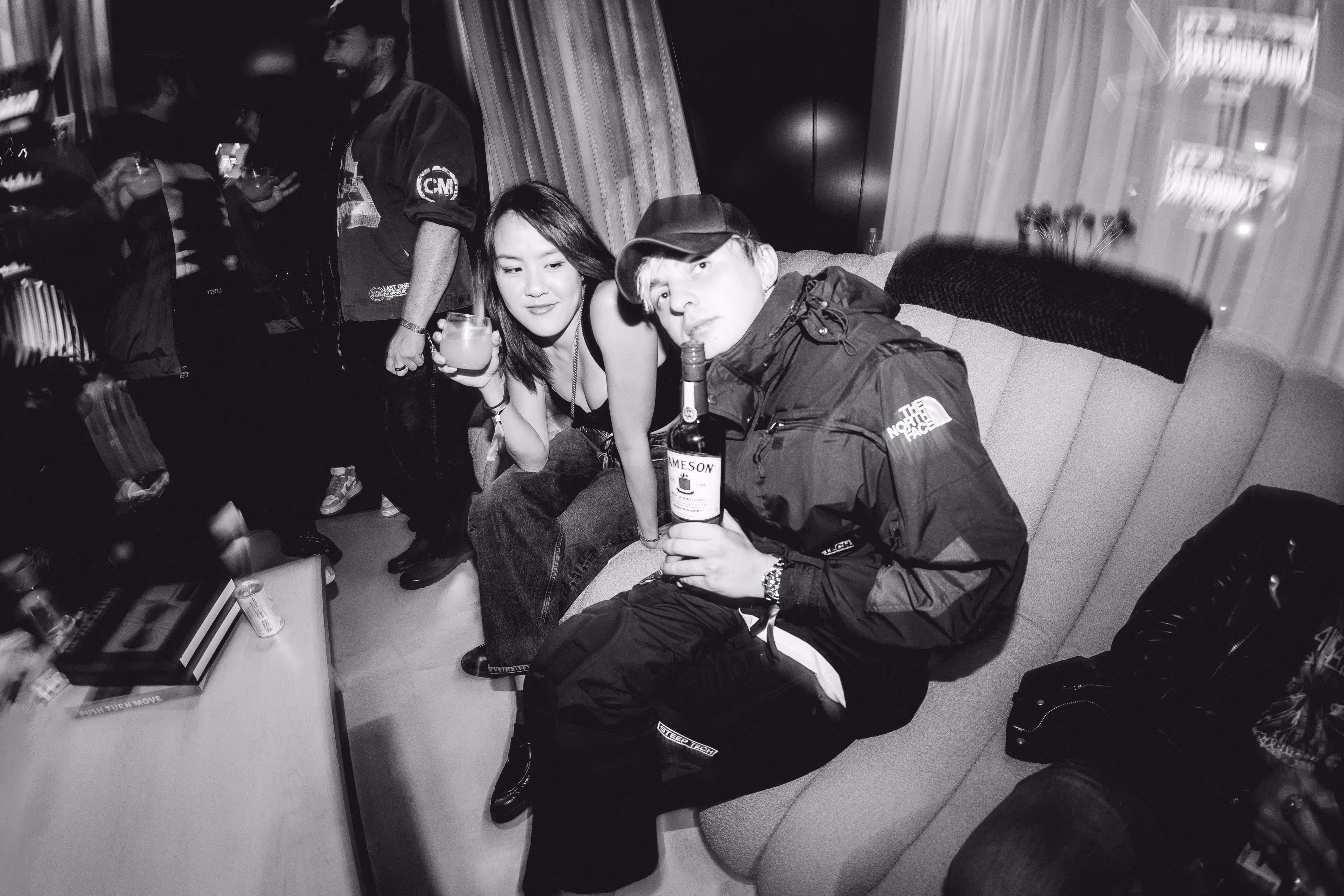 A man and a woman sitting on a couch with a bottle of wine.