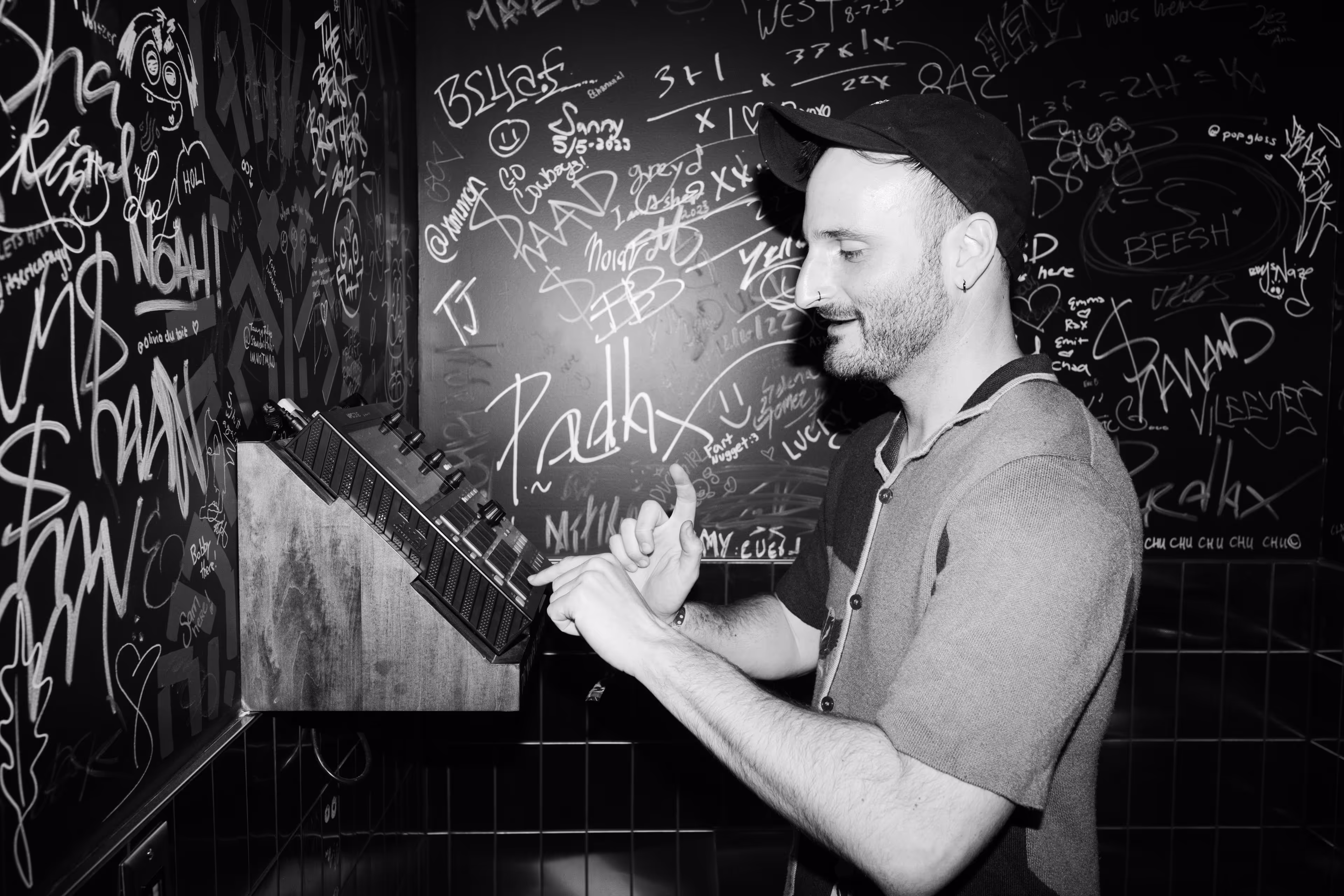A man standing in front of a wall covered in graffiti.