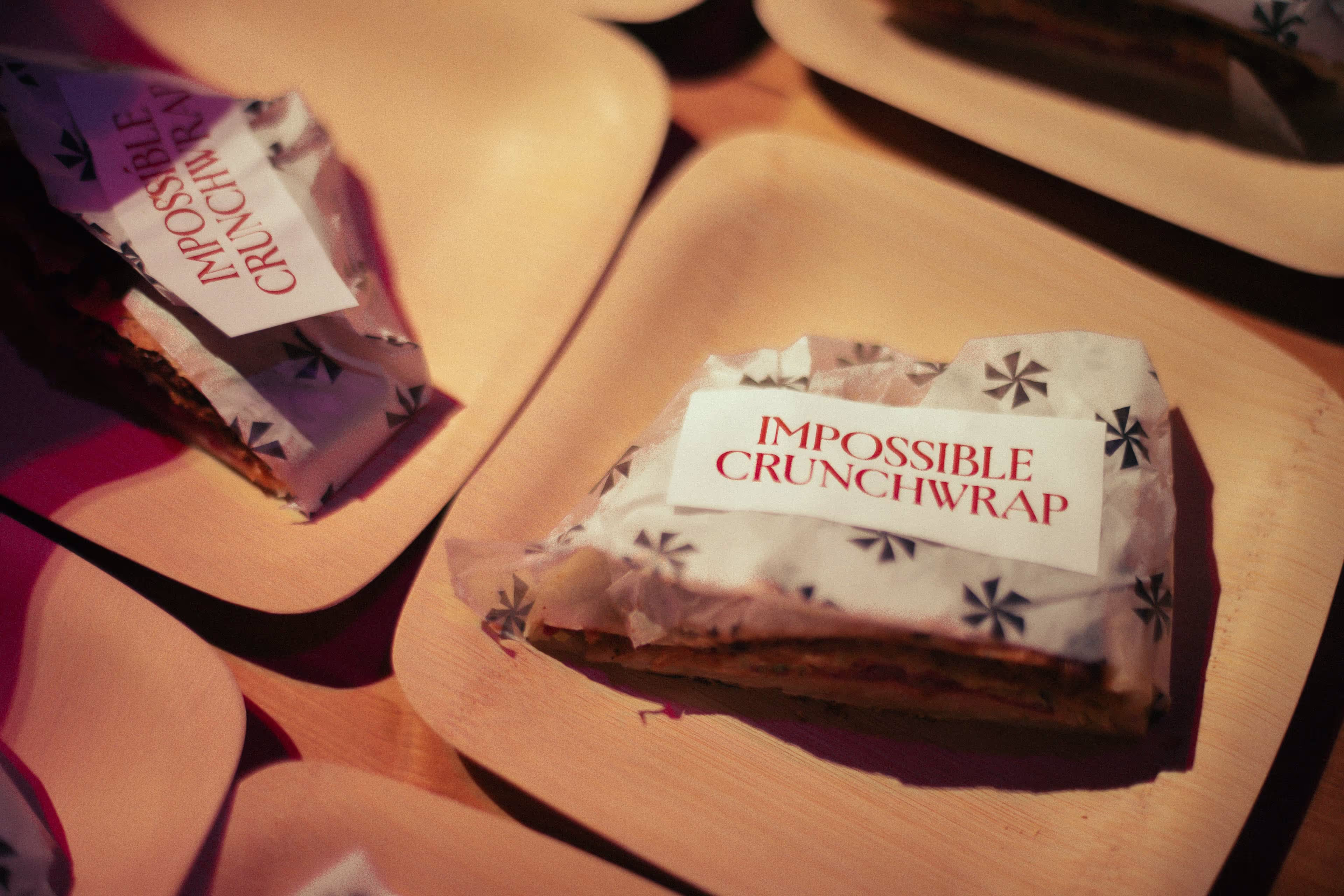 Wrapped Impossible Crunchwraps on wooden plates under warm lighting.