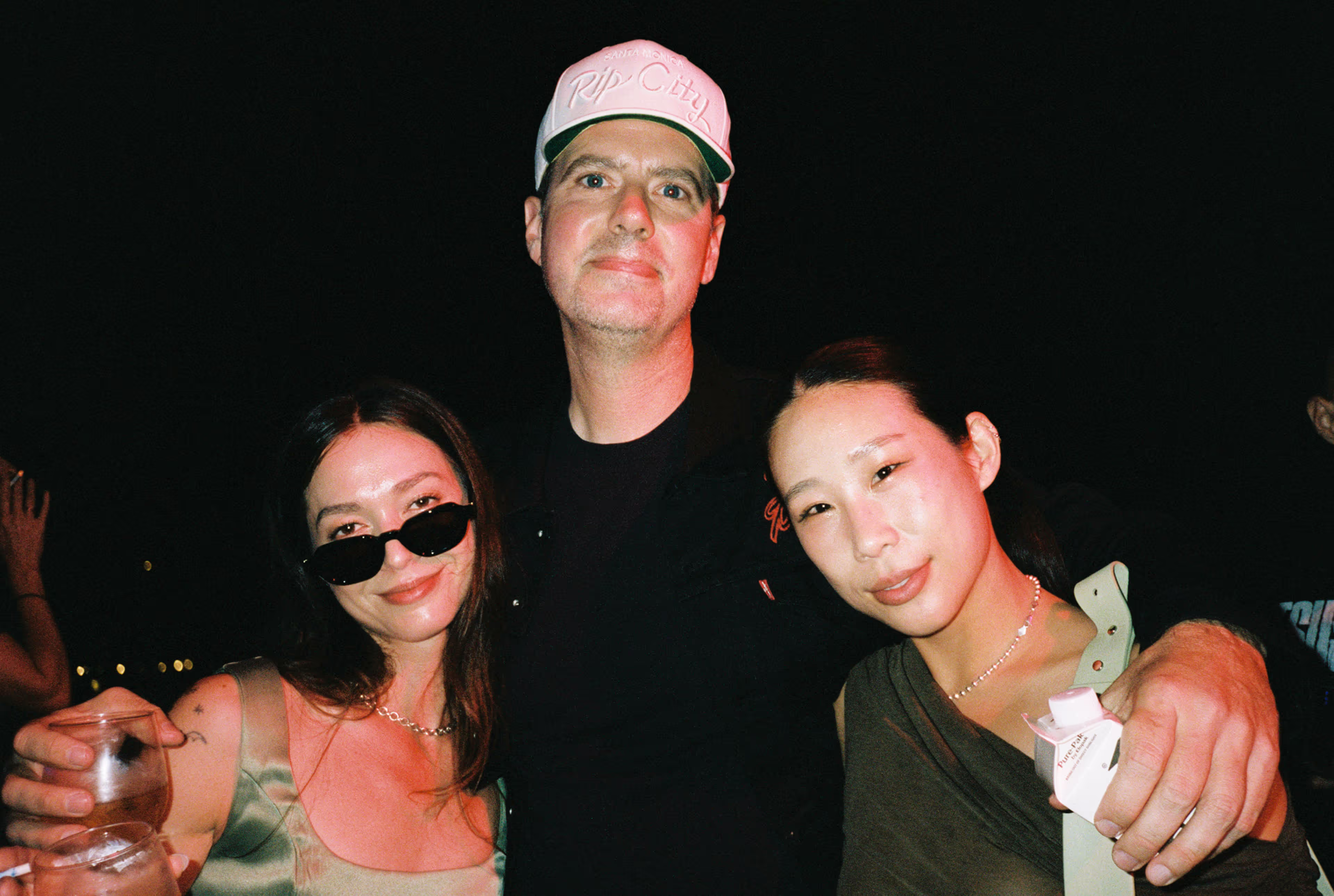 Three people posing together at night.