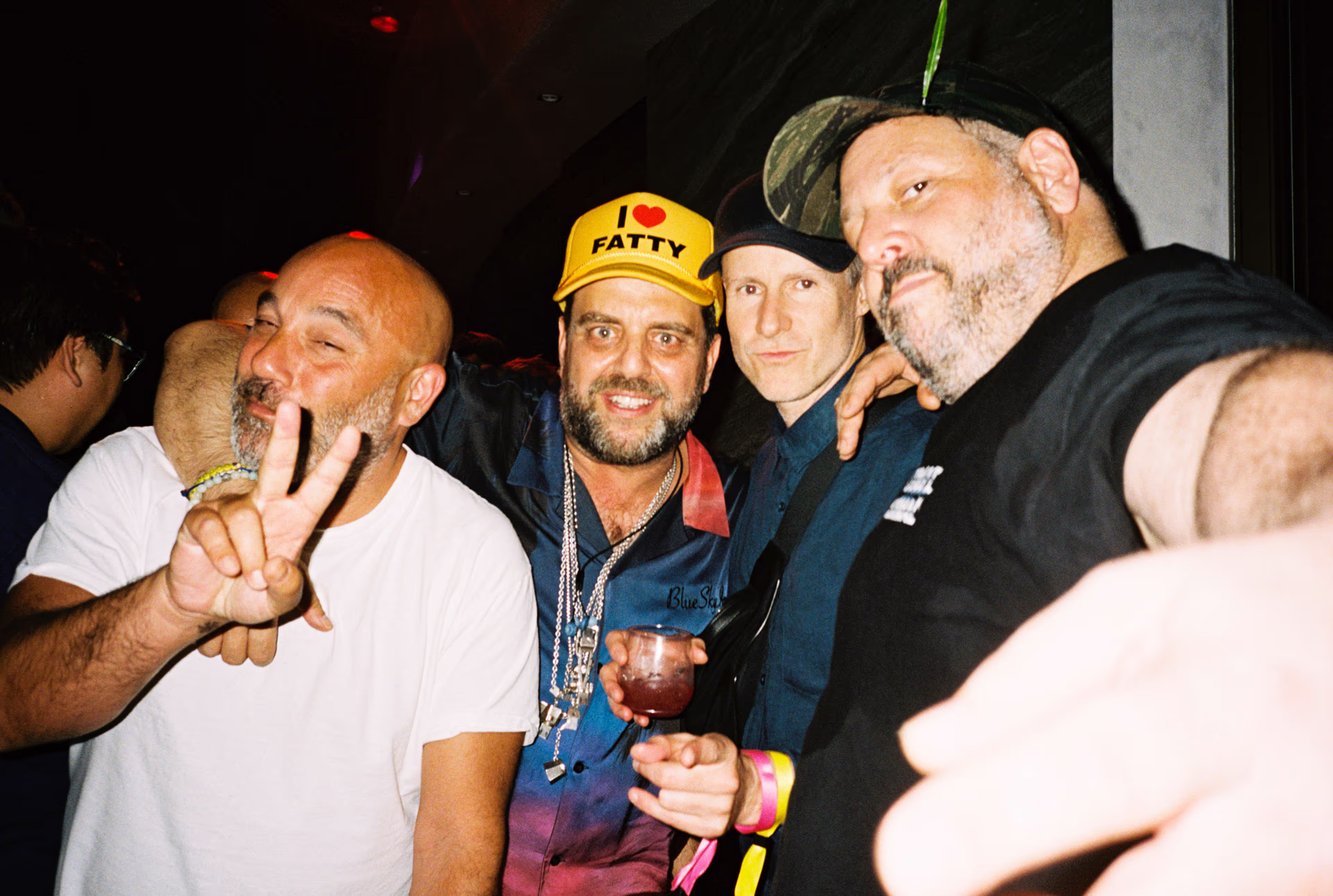 Four men closely posing for a photo at a party.