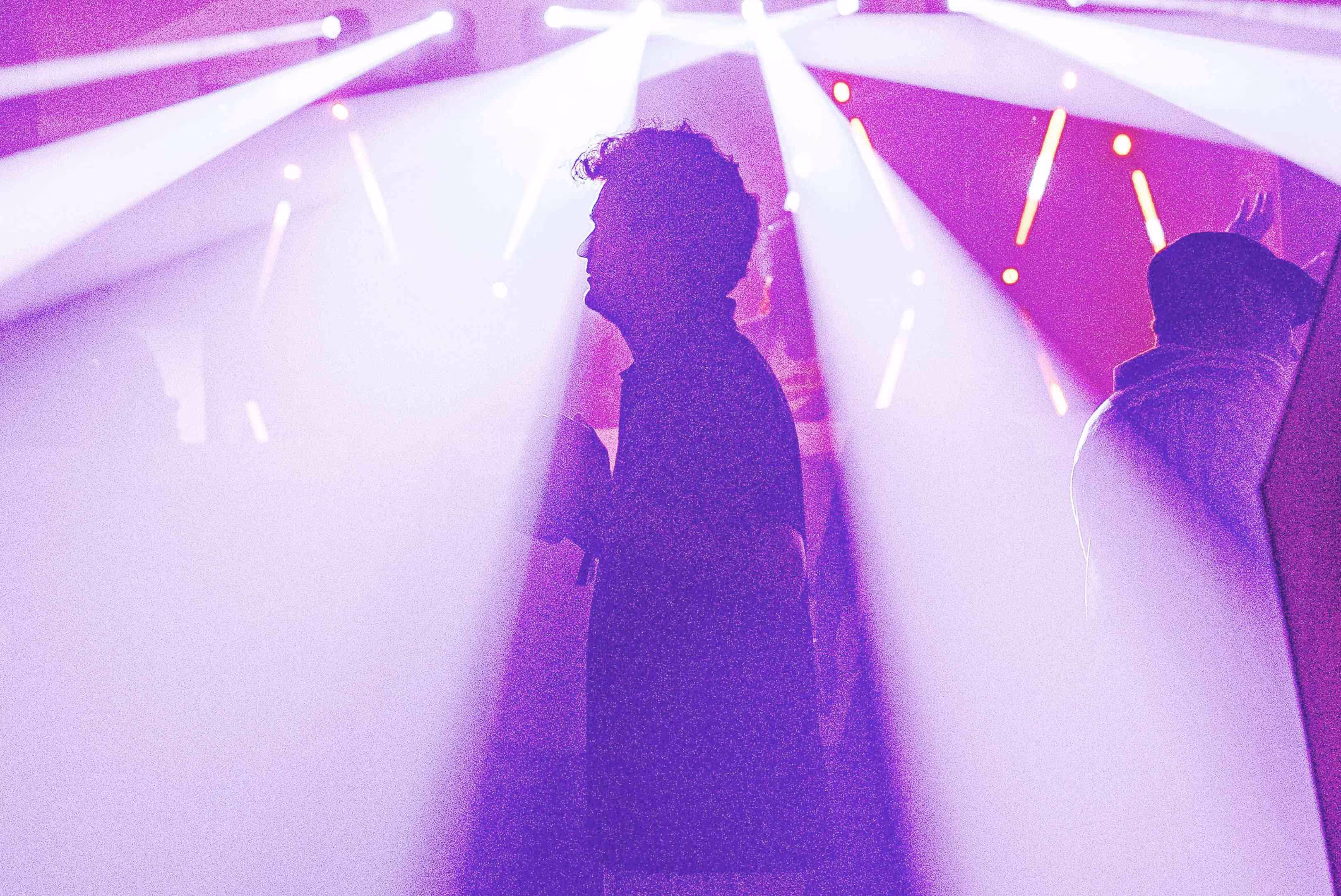 A woman standing in front of a purple light.