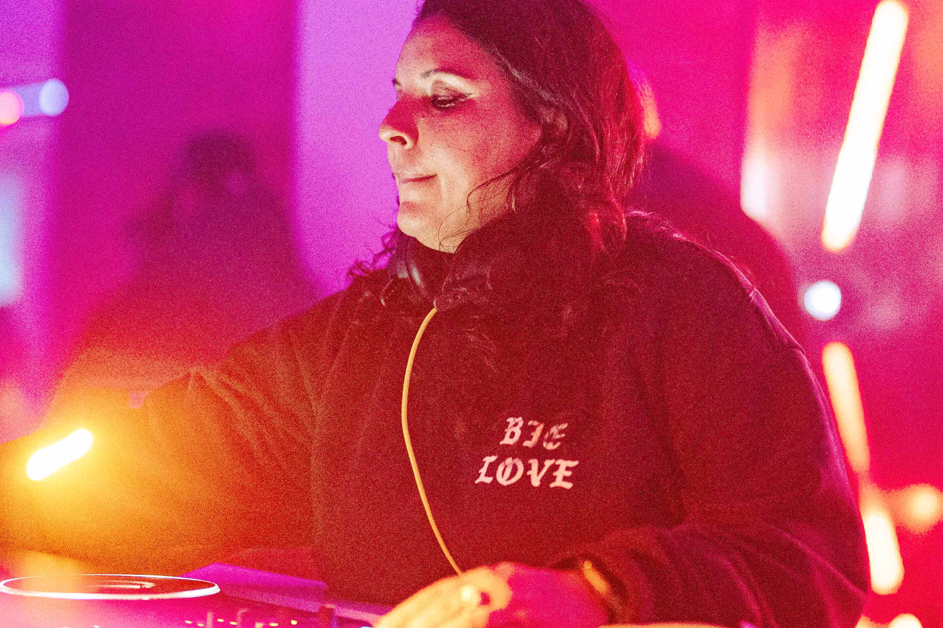 A woman in a black sweatshirt is playing a dj set.