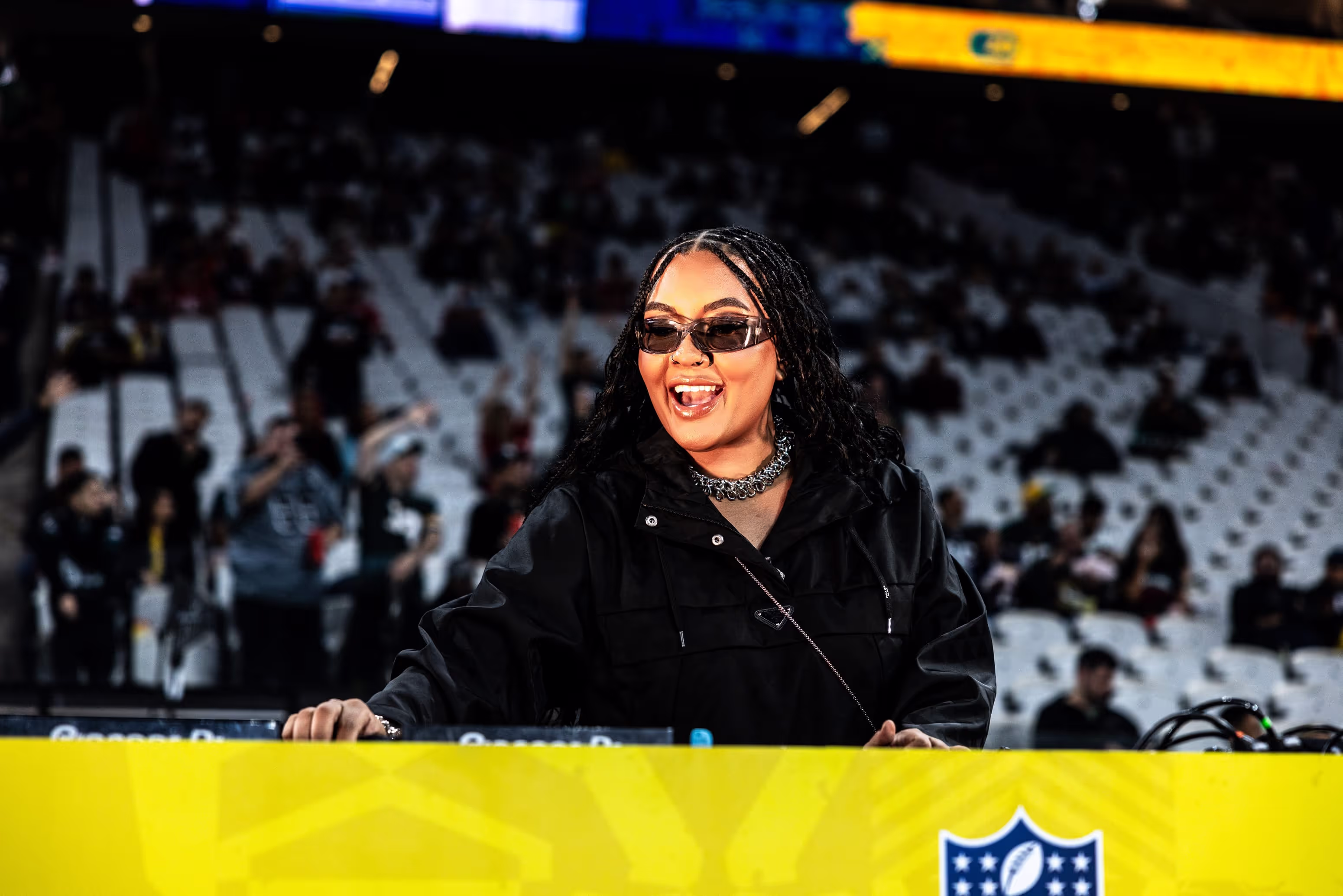 A woman in a black jacket and sunglasses standing at a podium.