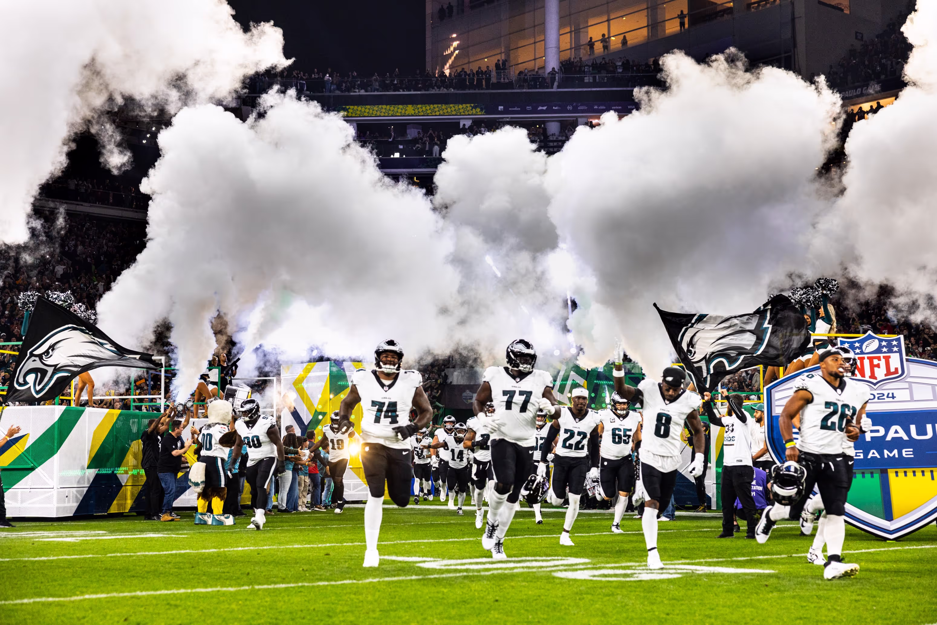 A group of football players running onto the field with co2
