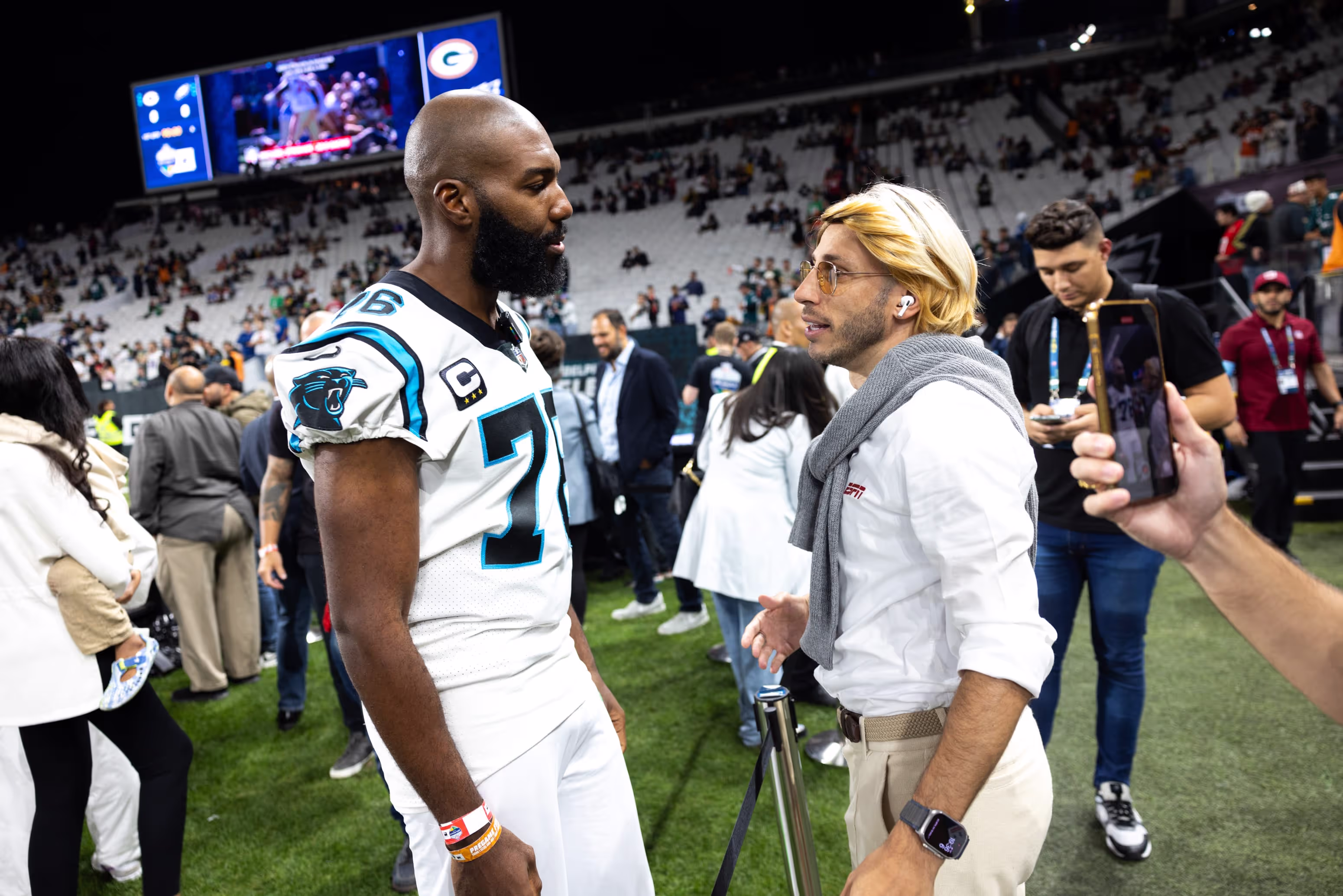 A man in a football uniform talking to another man.