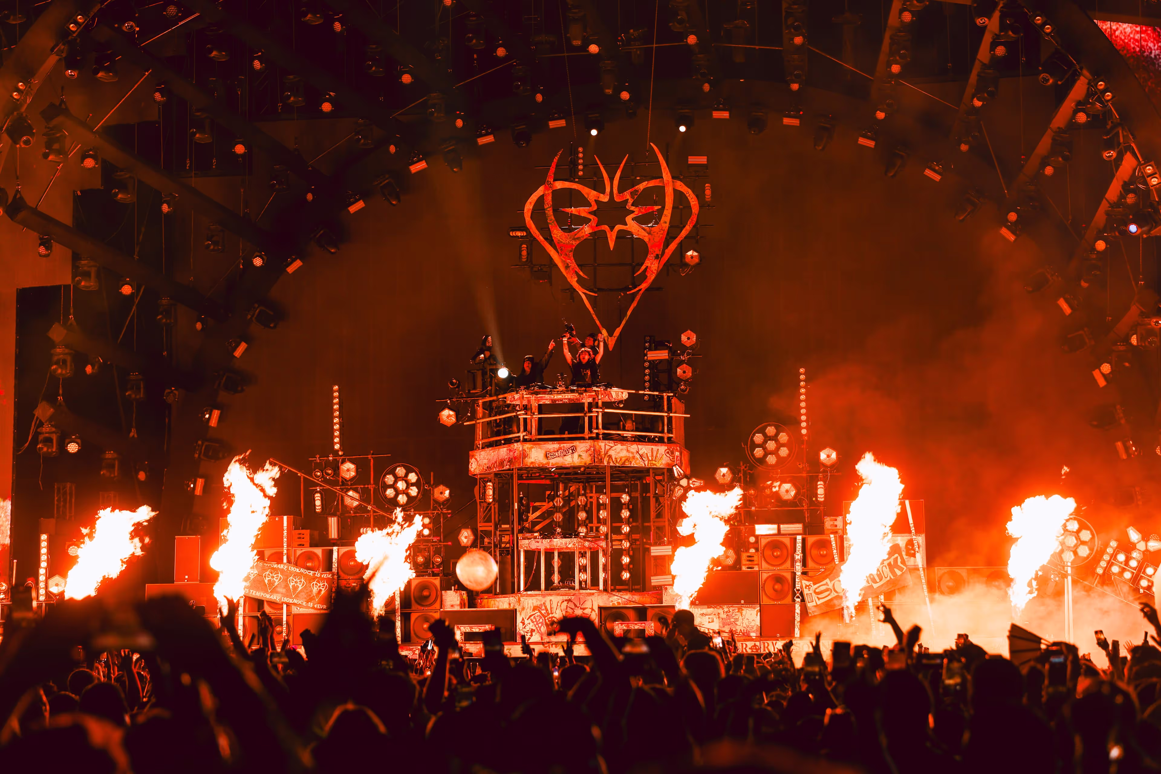 A crowd of people standing around a stage on fire.