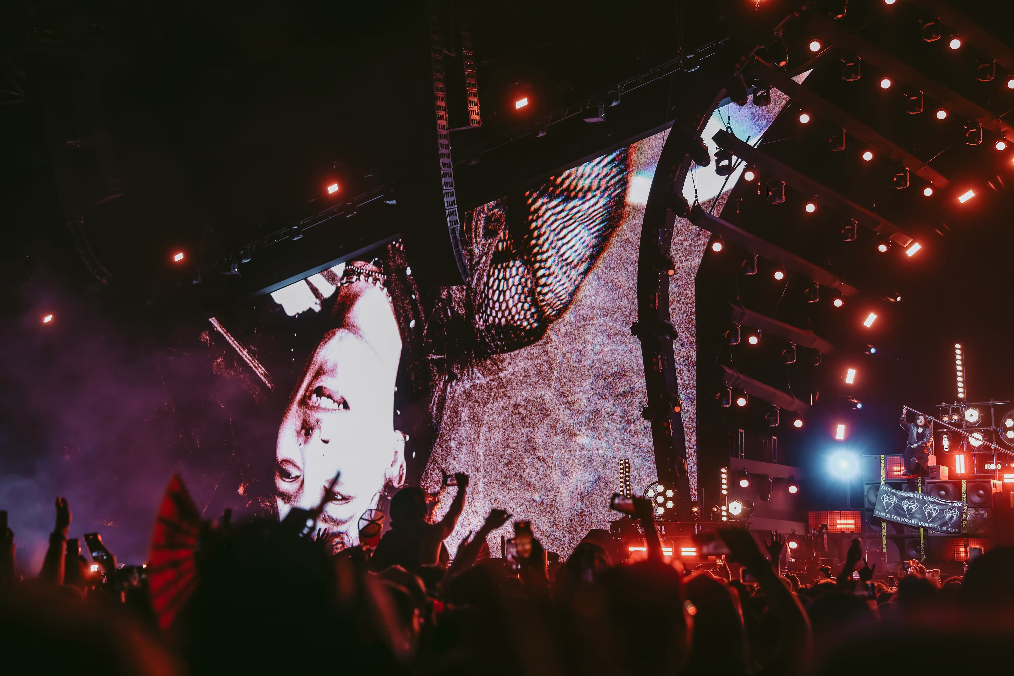 A crowd of people watching a concert on a large screen.